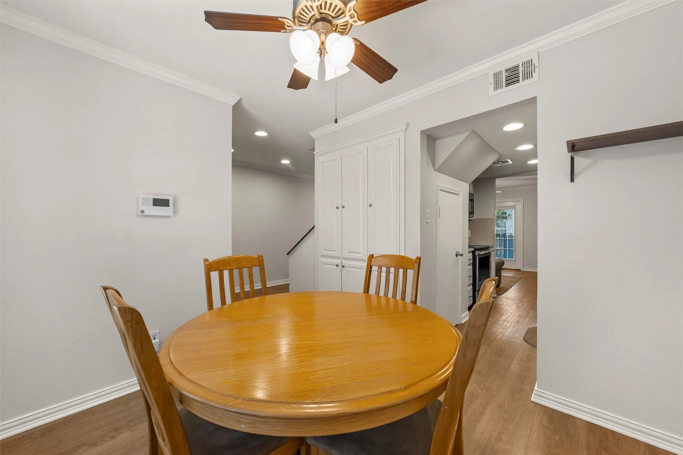 Dining area with ceiling fan, crown molding and great cabinet storage.