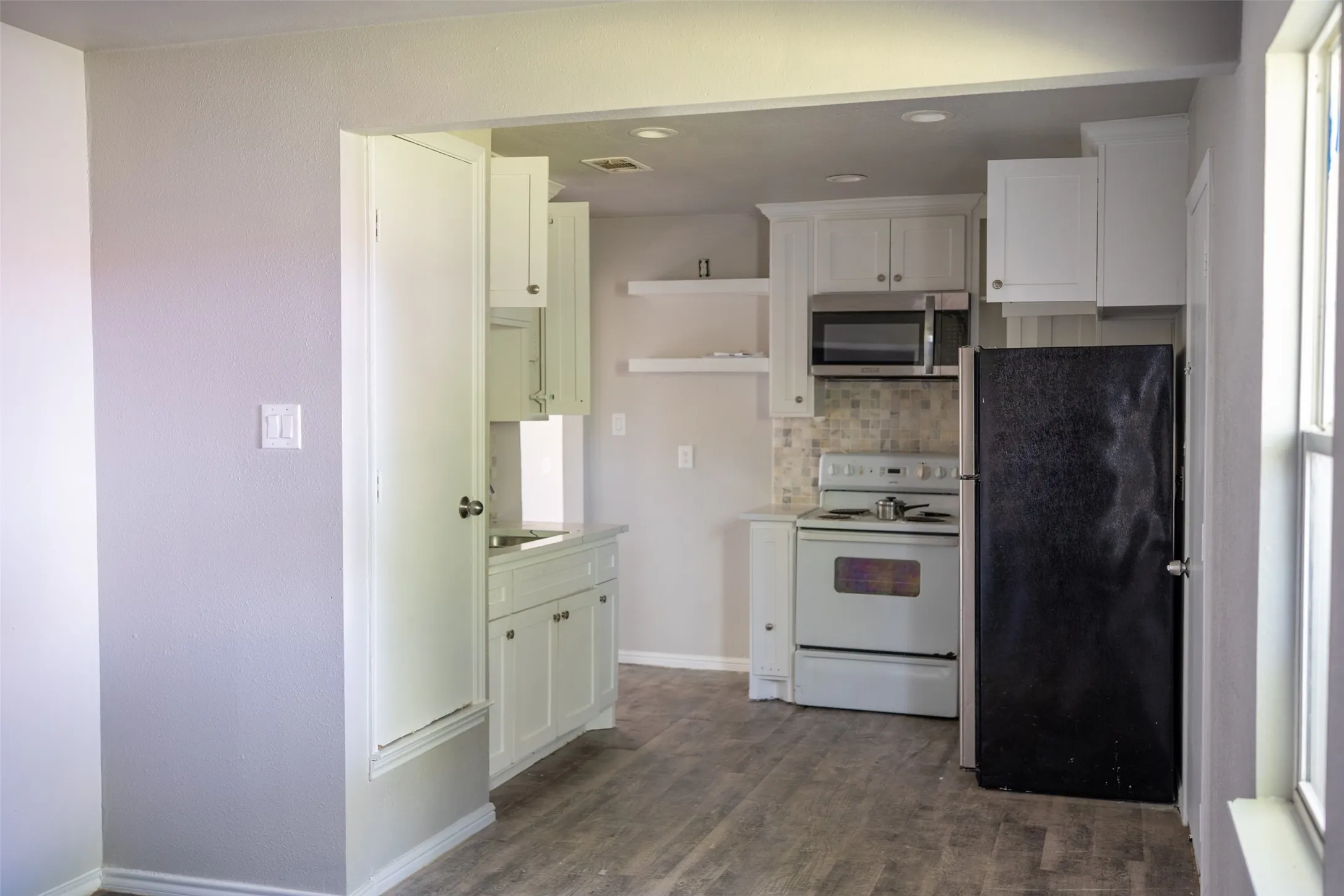 Kitchen with stainless steel appliances, tasteful backsplash, light countertops, recessed lighting, and dark wood-style flooring