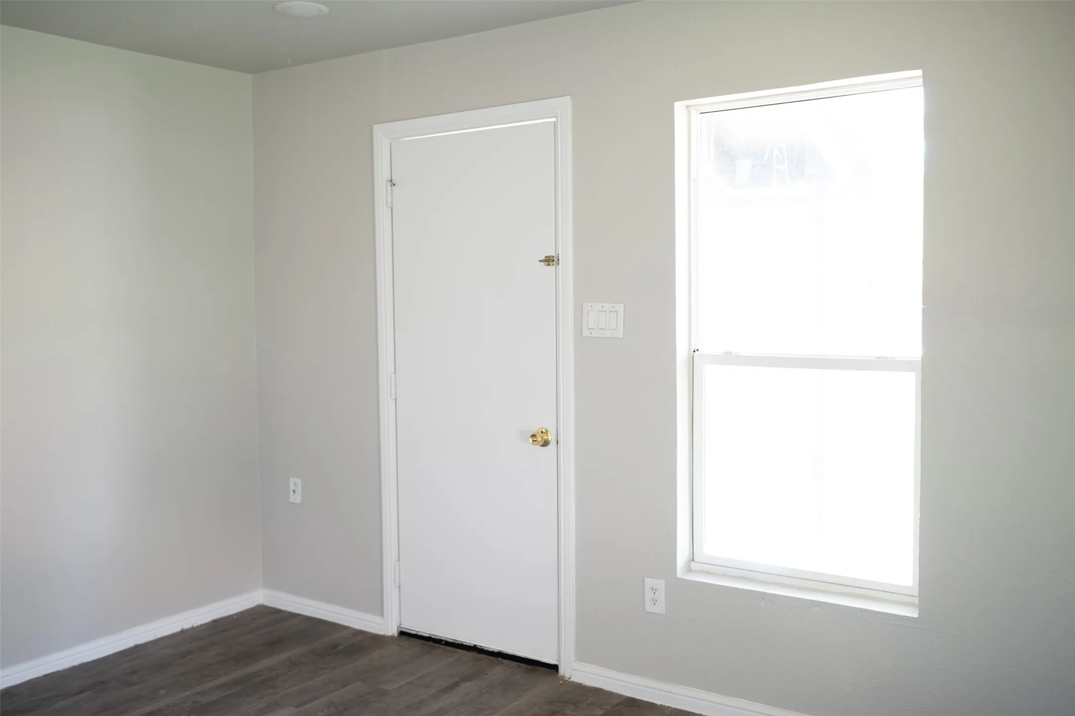 Unfurnished bedroom with baseboards and dark wood finished floors