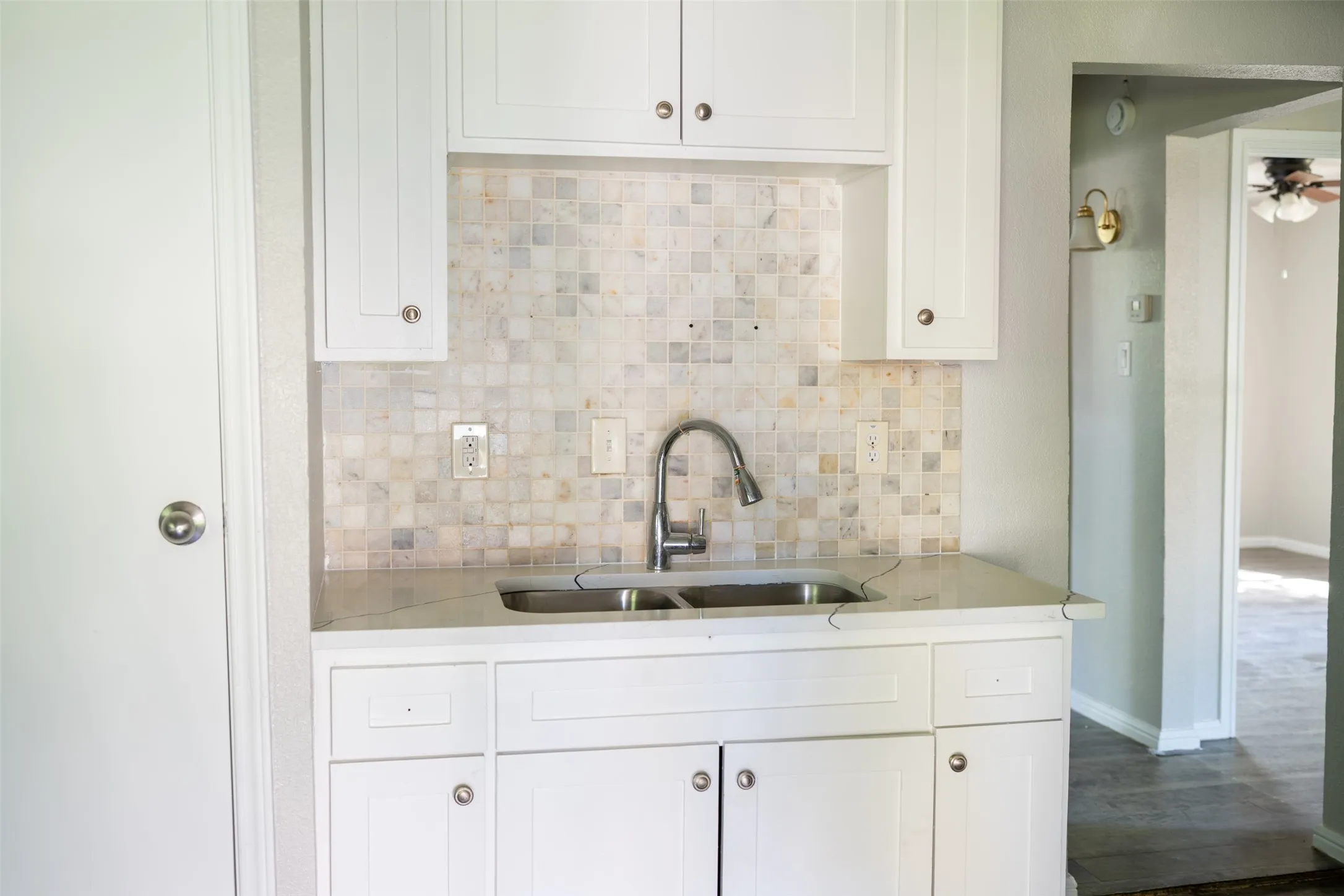 Kitchen with white cabinetry, tasteful backsplash, light stone countertops, and dark wood-style floors