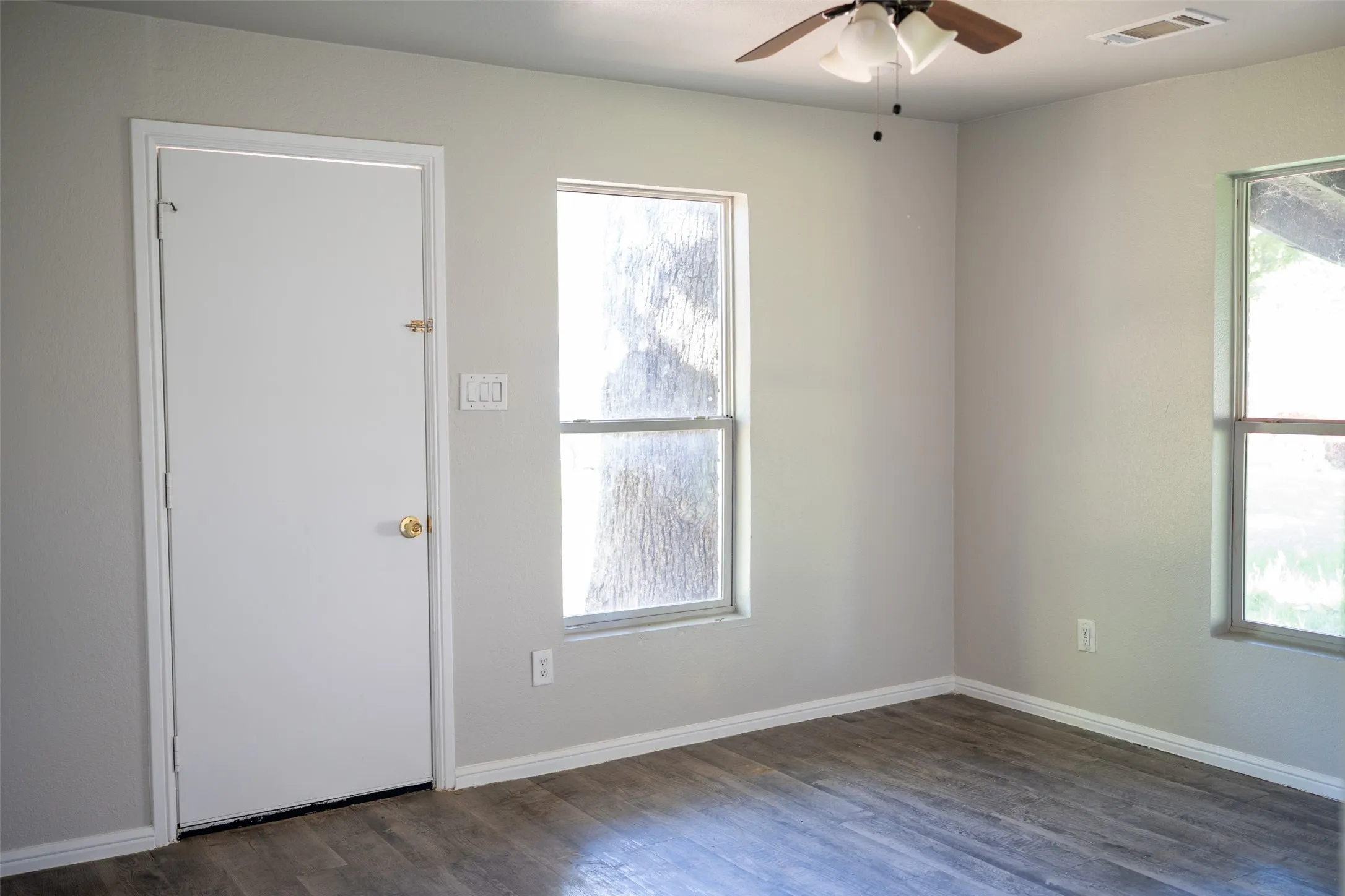 Empty room with a ceiling fan and dark wood finished floors