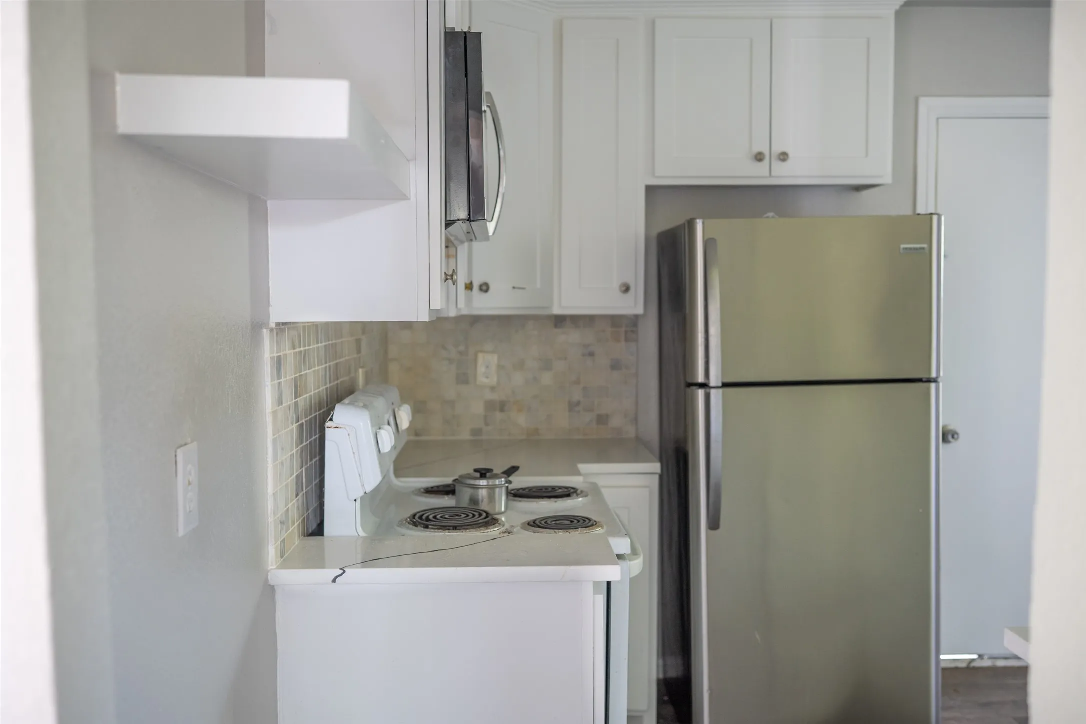 Kitchen with stainless steel appliances, white cabinets, and backsplash