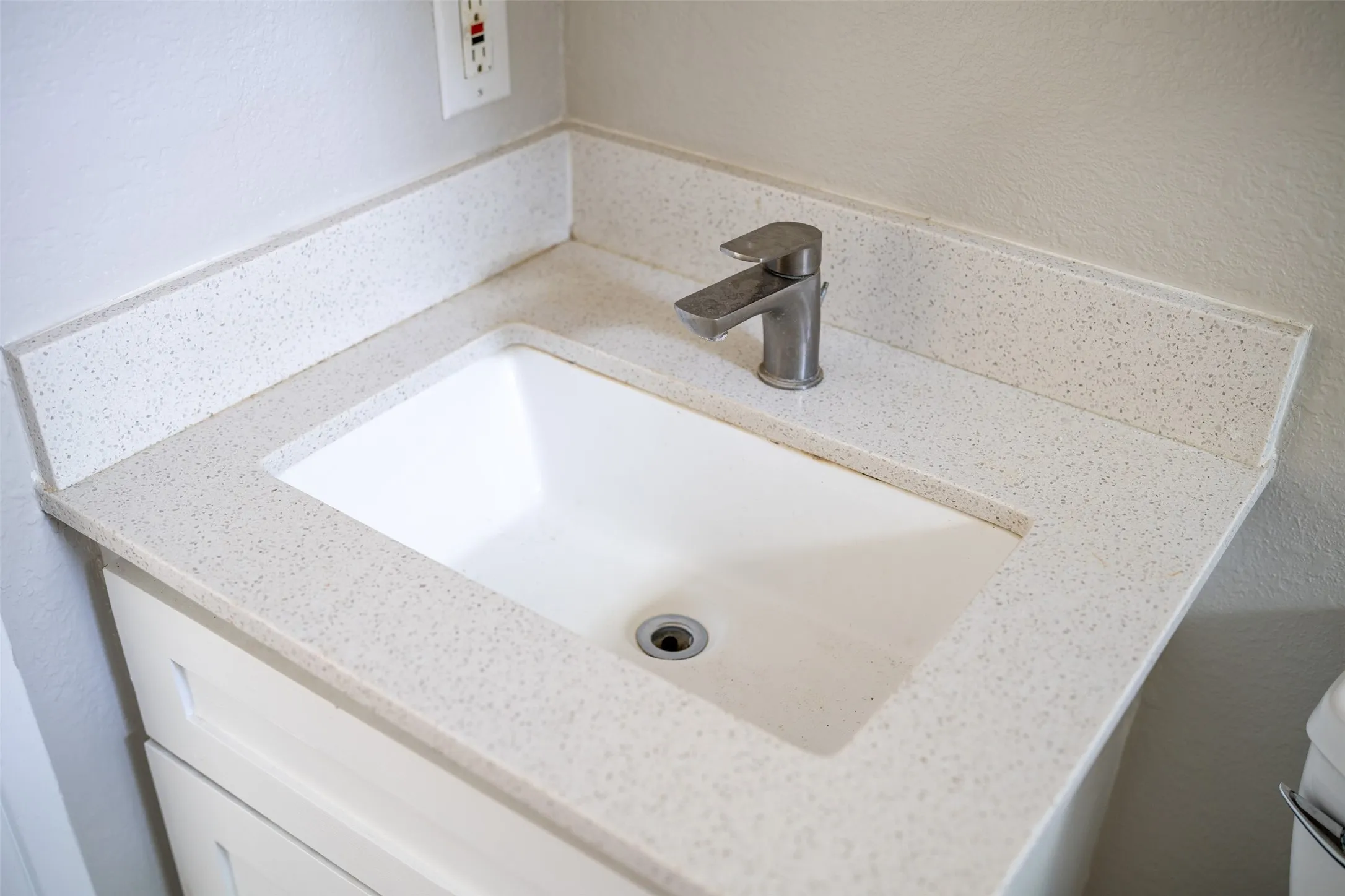 Bathroom view of vanity and a textured wall