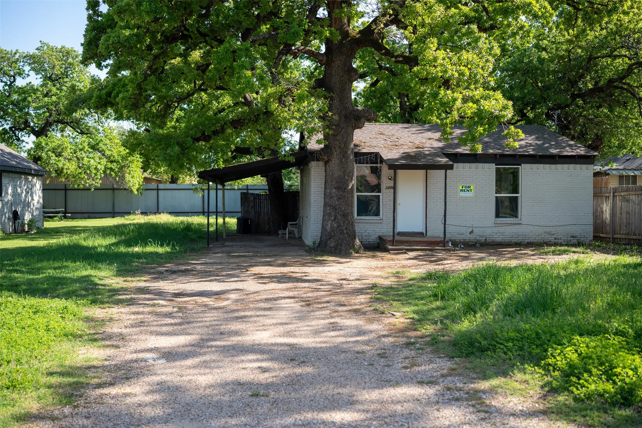 View of front facade with brick siding, driveway, and a carport
