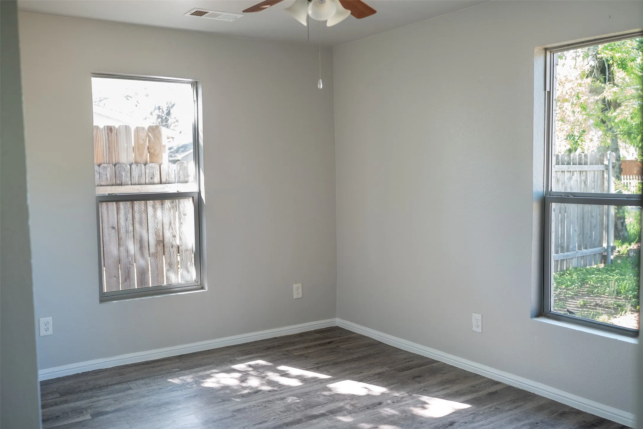 Unfurnished room featuring a ceiling fan and dark wood-type flooring