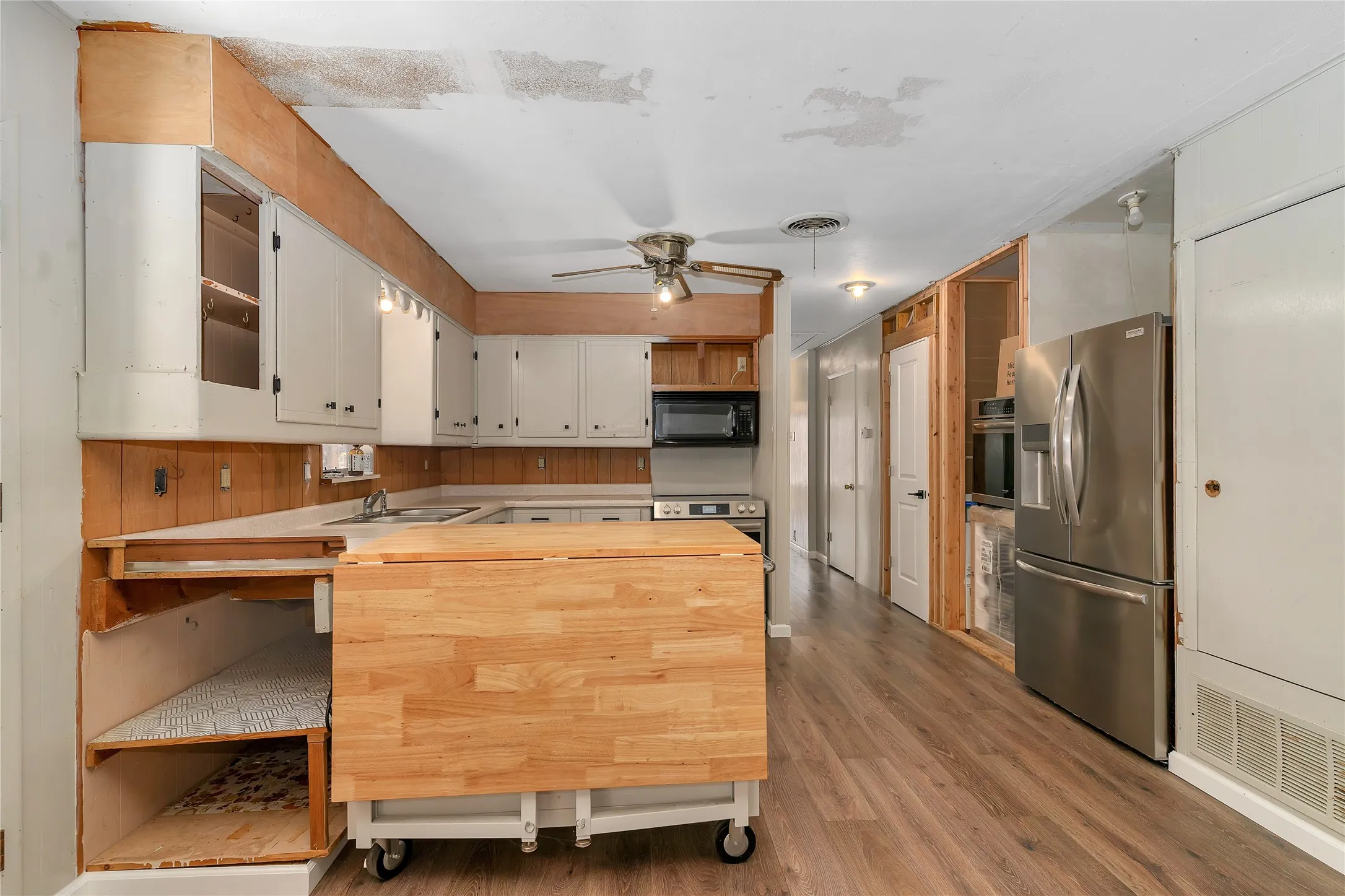 Kitchen with a peninsula, stainless steel appliances, open shelves, light wood finished floors, and a ceiling fan