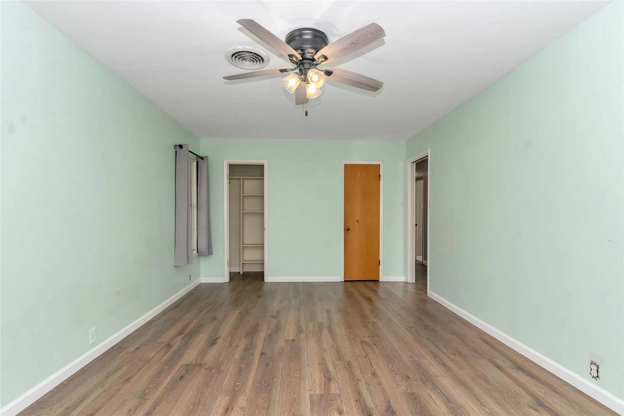 Unfurnished bedroom with wood finished floors, two closets, and ceiling fan