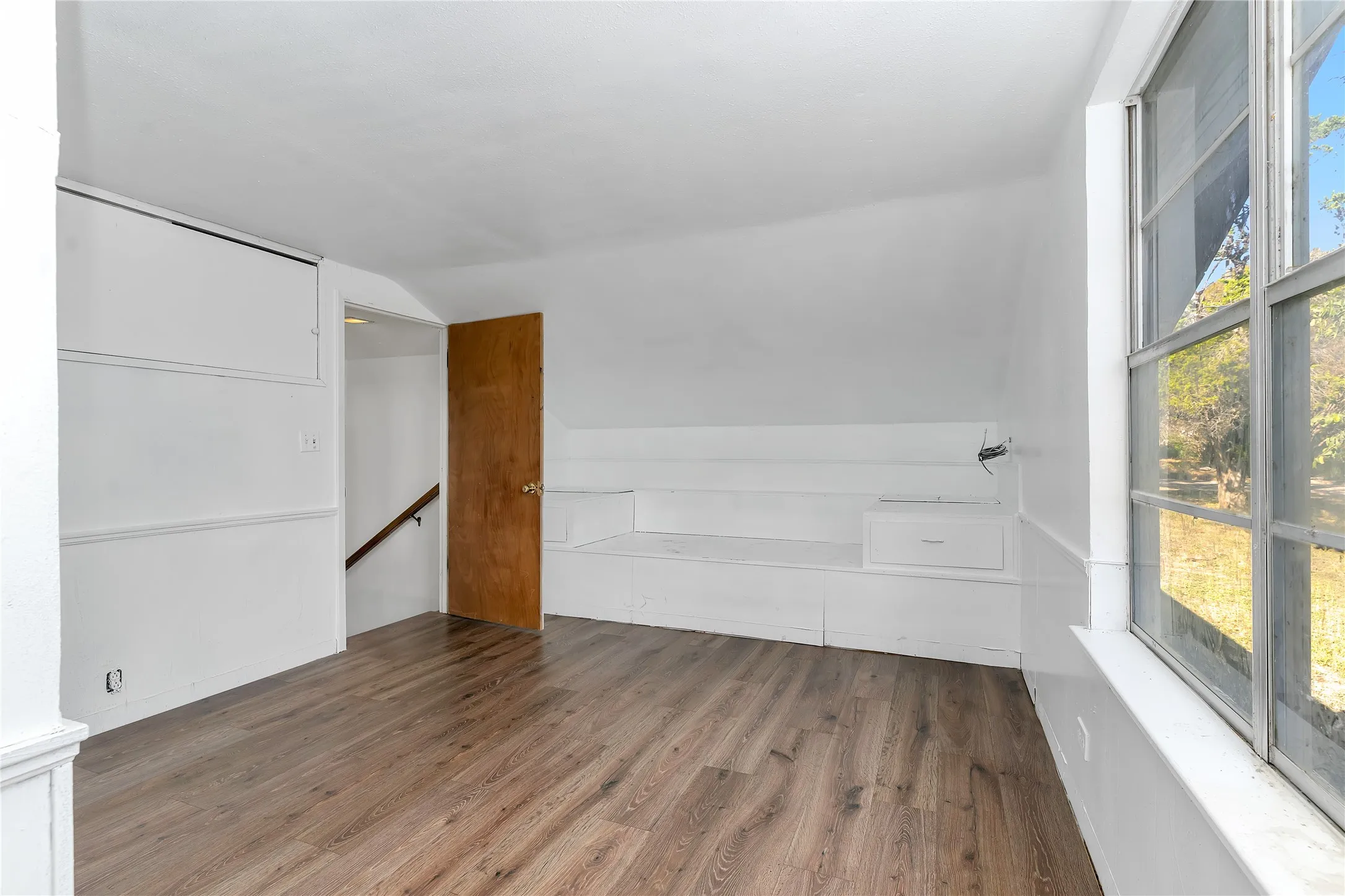 Empty room with wood finished floors and lofted ceiling