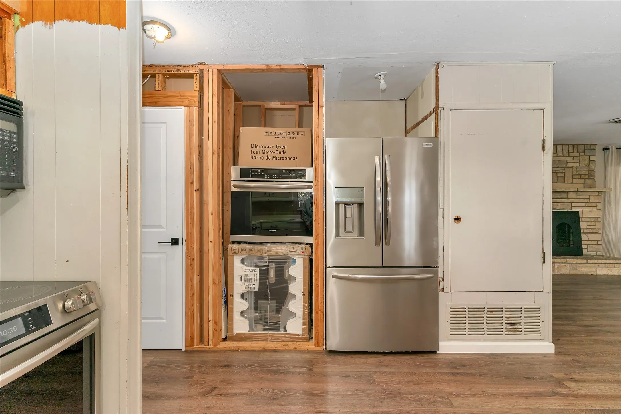 Kitchen featuring stainless steel appliances, light wood-style flooring, and a stone fireplace