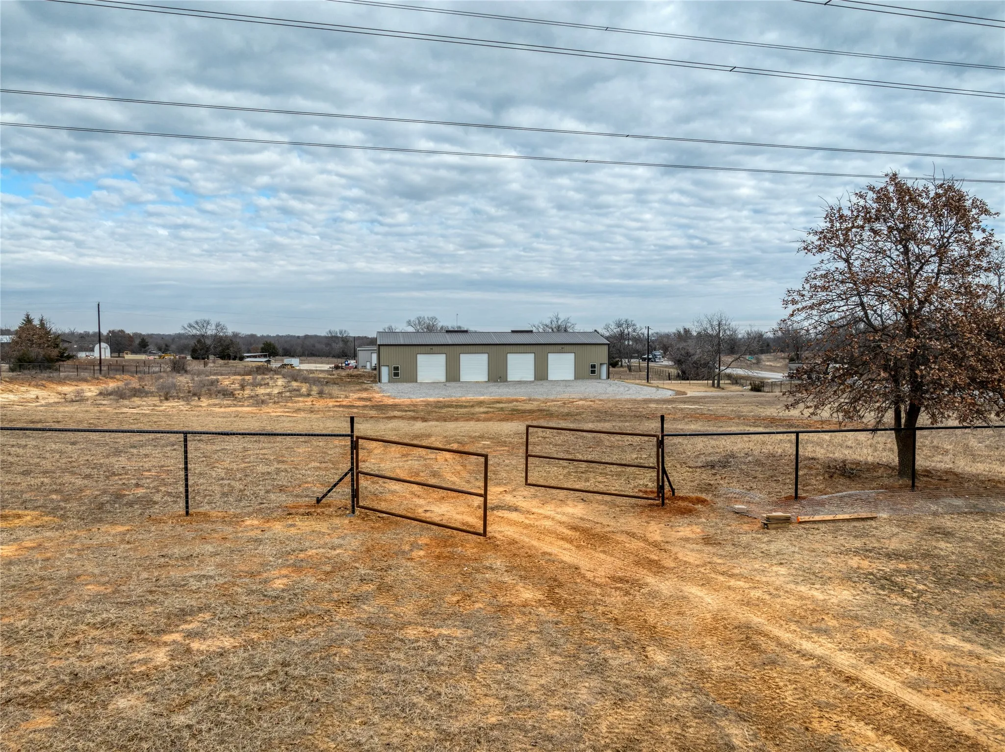 View of yard featuring a gate, an outbuilding, a garage, driveway, and a view of countryside