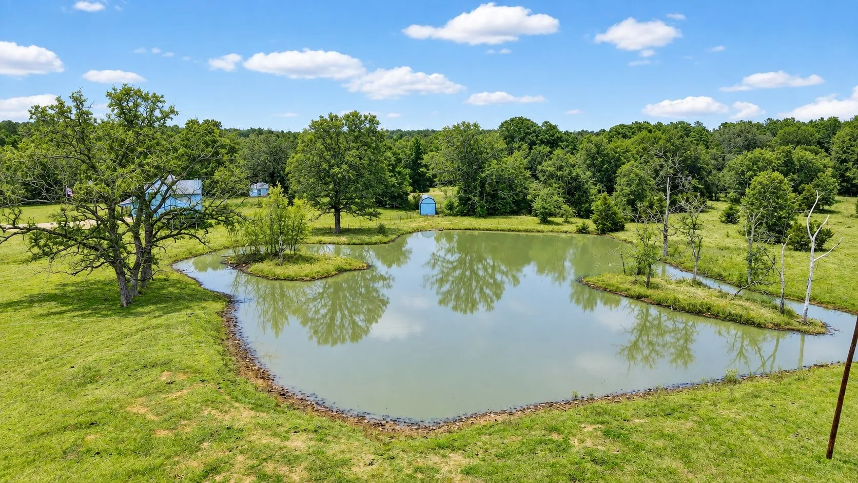 Private pond with a central island, surrounded by expansive green grounds and mature trees
