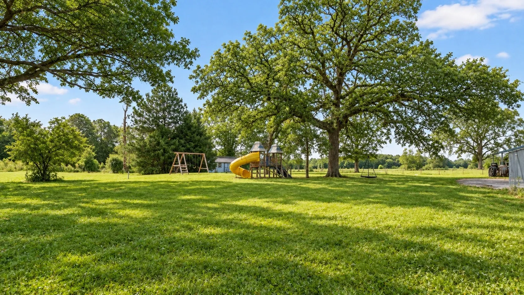 Expansive green lawn with mature trees and a swing set