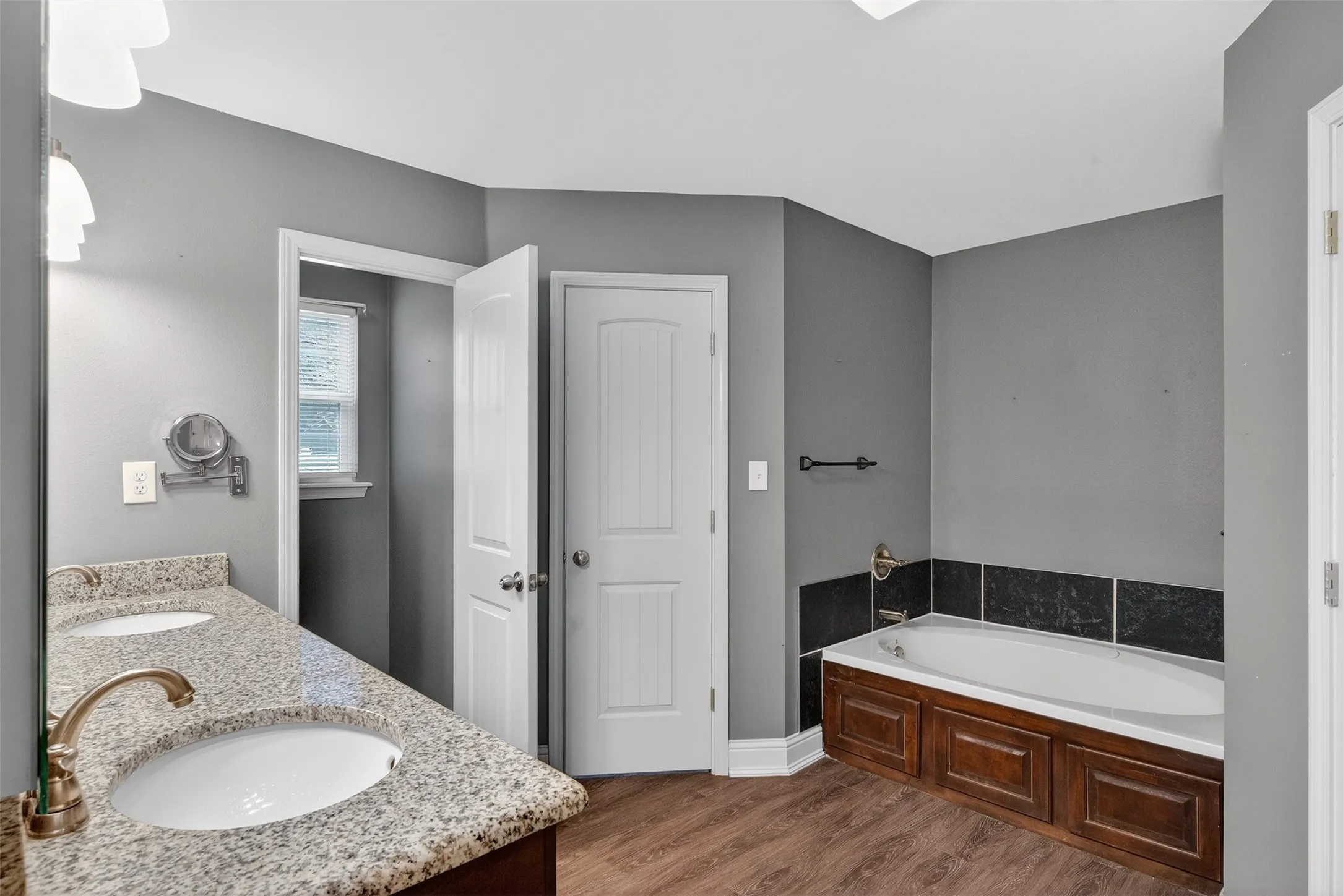 Full bathroom with a bath, dark wood-style floors, and double vanity
