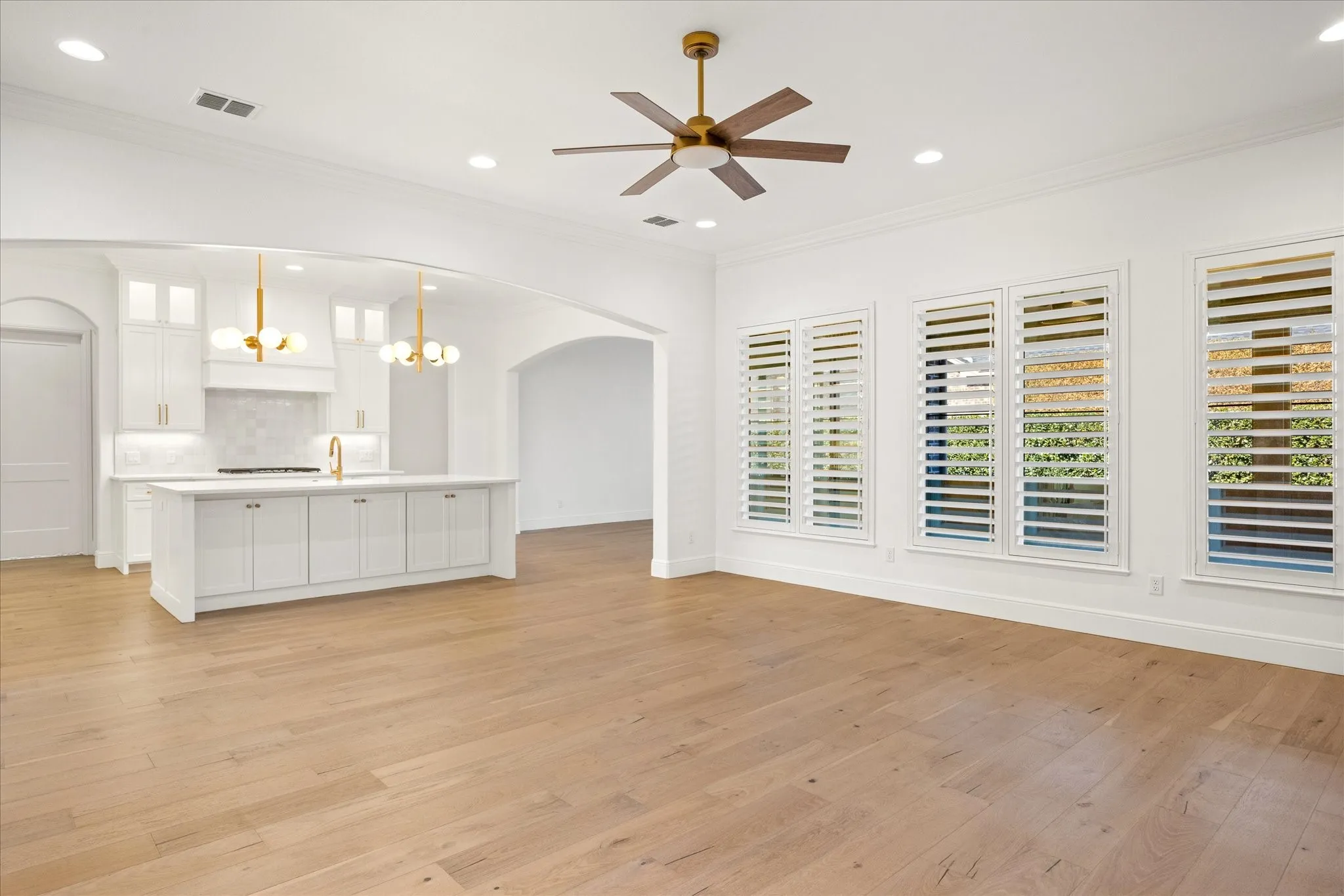 Unfurnished living room with a chandelier, ornamental molding, light wood-type flooring, recessed lighting, and healthy amount of natural light