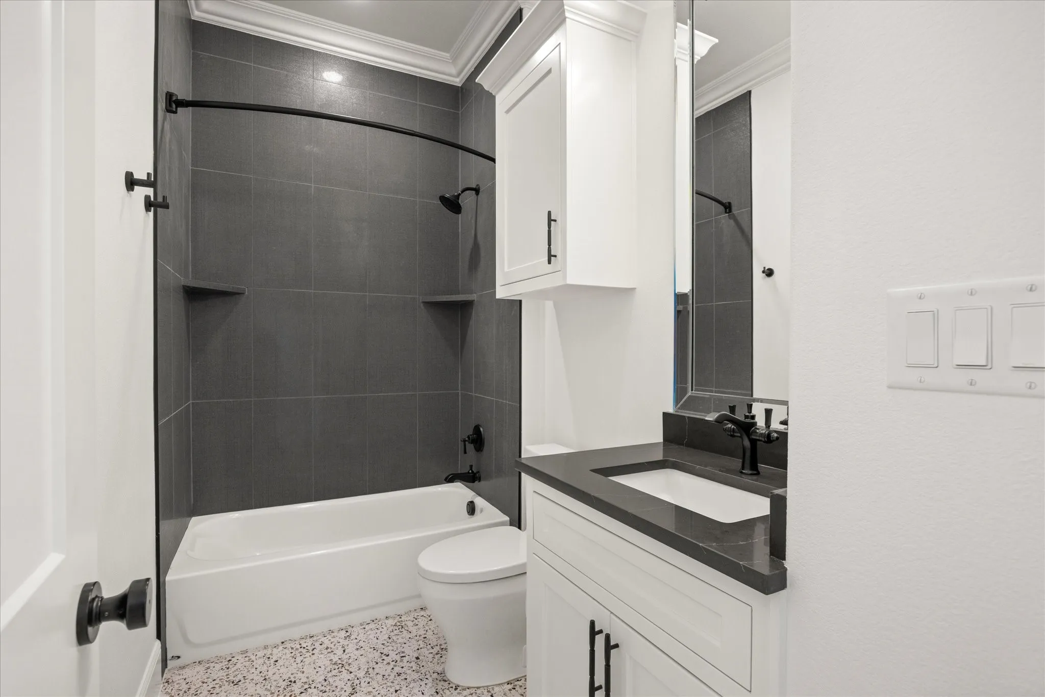 Bathroom featuring speckle patterned floor,  shower combination, vanity, and crown molding