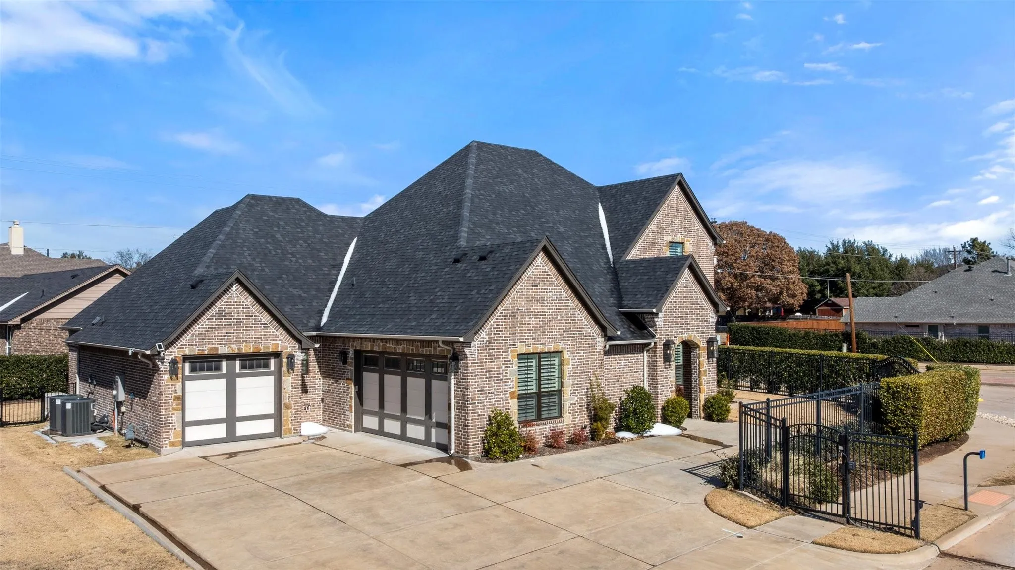 View of front of home featuring driveway, brick siding, roof with shingles, and a garage