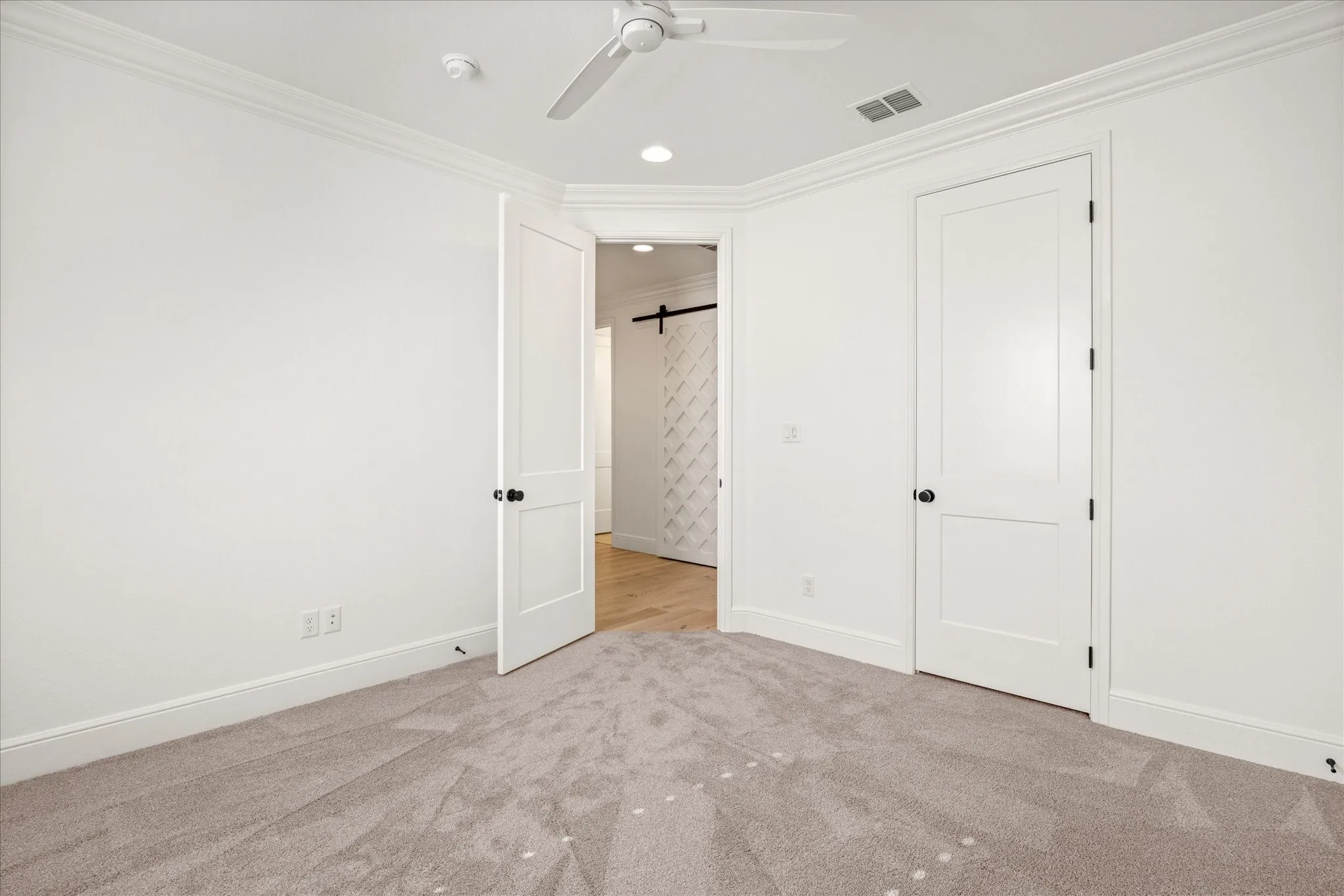 Unfurnished bedroom 1 featuring a barn door, crown molding, light colored carpet, ceiling fan, and recessed lighting