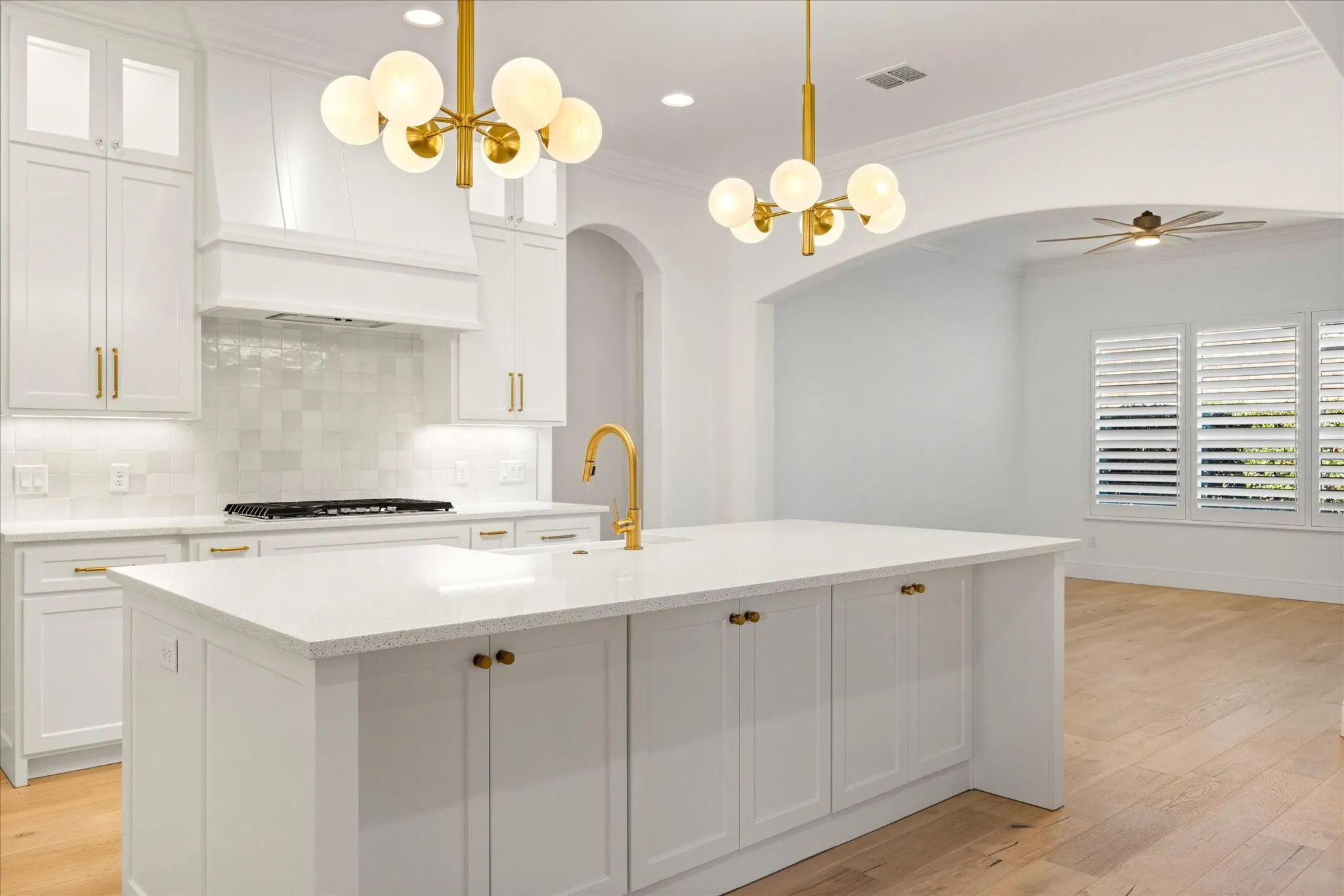 Kitchen featuring white cabinetry, pendant lighting, glass insert cabinets, a chandelier, and light wood-type flooring