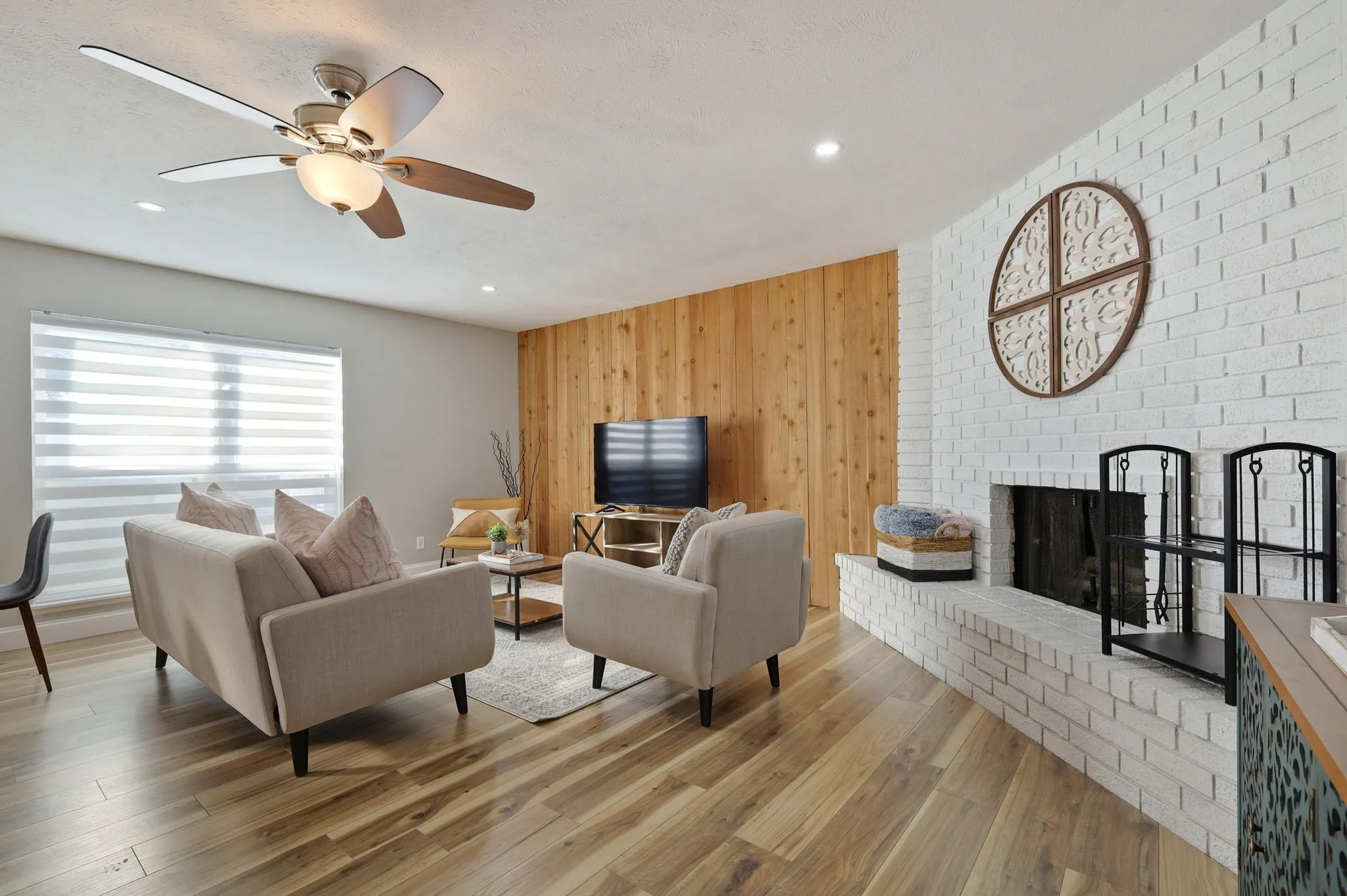 Living room featuring ceiling fan, a fireplace, wood-type flooring, and wooden walls