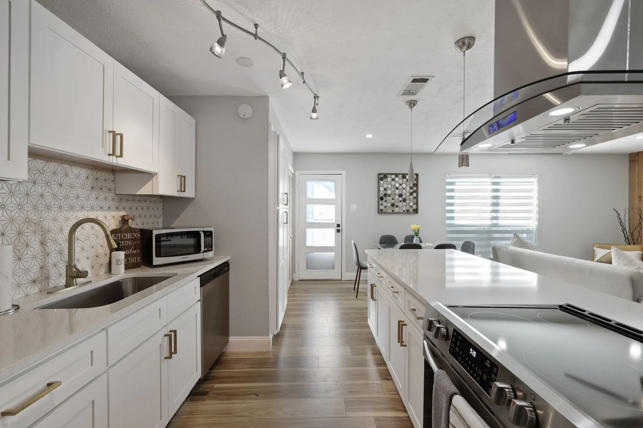 Kitchen featuring sink, stainless steel appliances, decorative light fixtures, decorative backsplash, and white cabinets