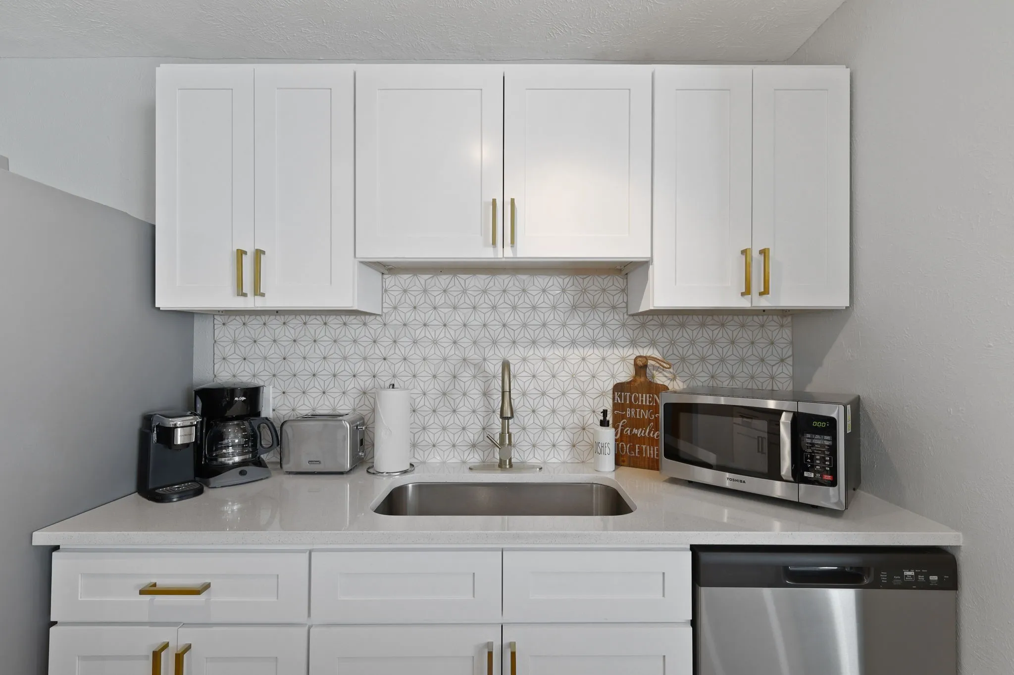 Kitchen with decorative backsplash, stainless steel appliances, white cabinetry, and sink