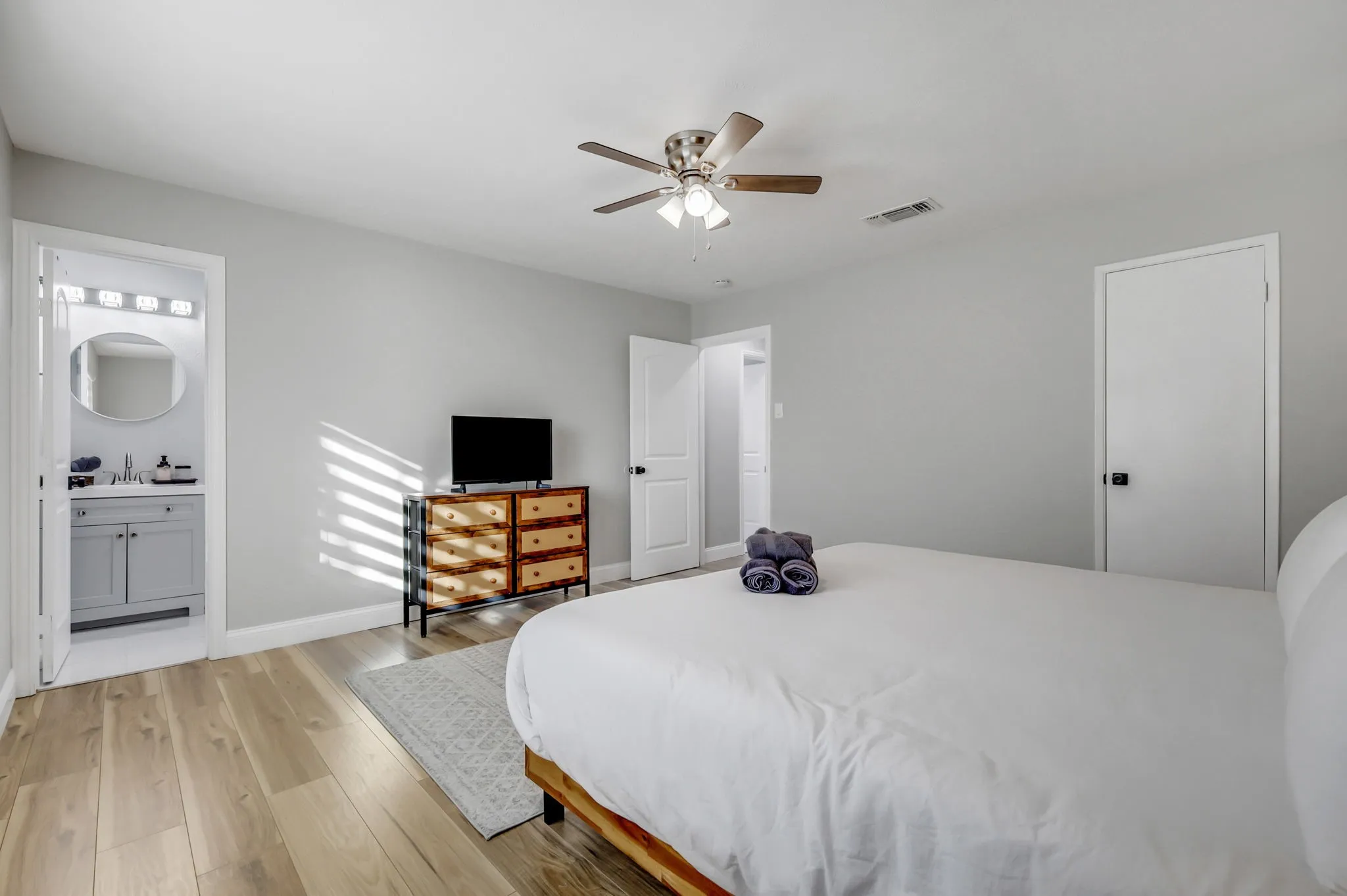 Bedroom with ensuite bathroom, light hardwood / wood-style flooring, and ceiling fan
