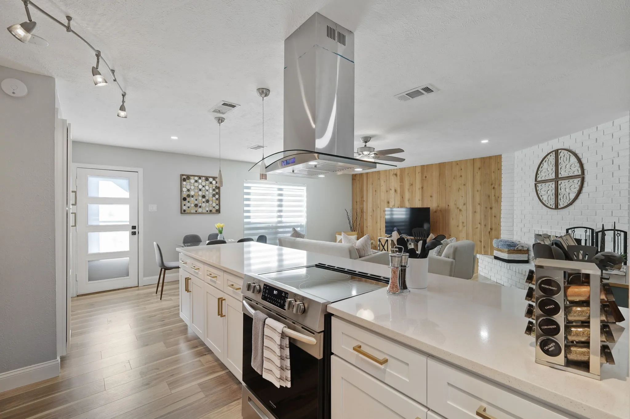 Kitchen featuring wooden walls, electric range, ceiling fan, island range hood, and white cabinetry