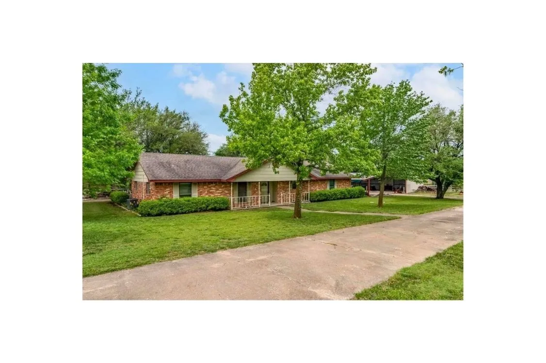 Ranch-style house with a front lawn, covered porch, and brick siding