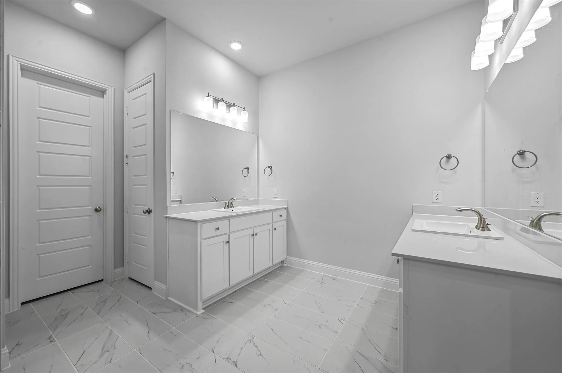Full bath with two vanities, light marble finish floors, and recessed lighting