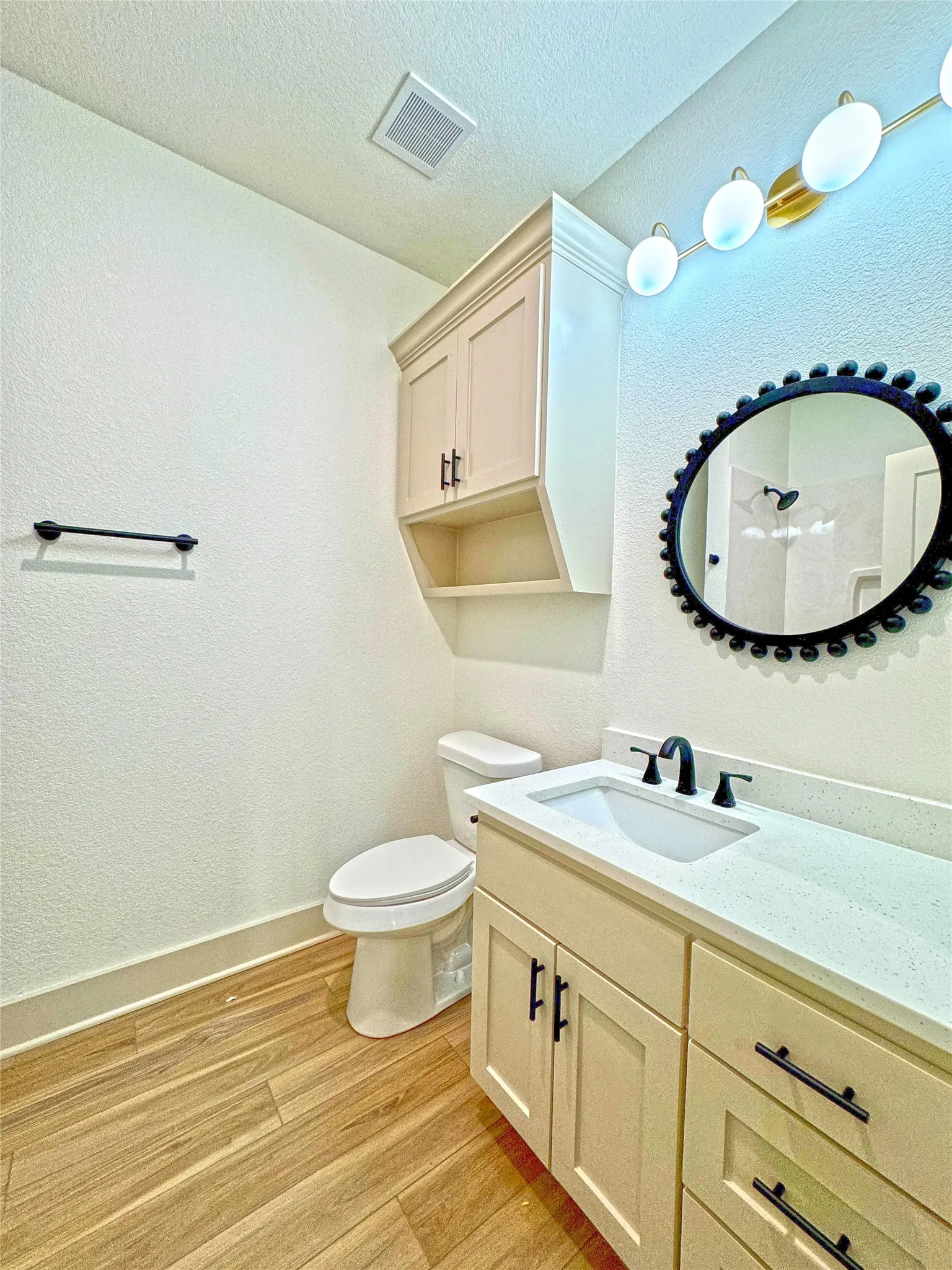 Bathroom with vanity, light wood-type flooring, and a textured wall
