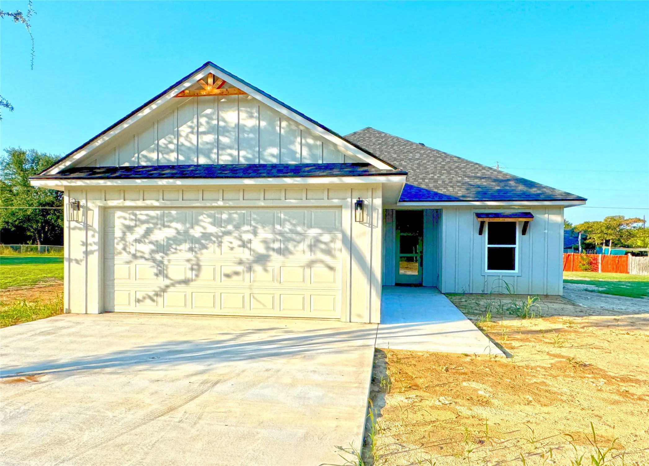 View of front of house with a shingled roof, a garage, board and batten siding, and driveway