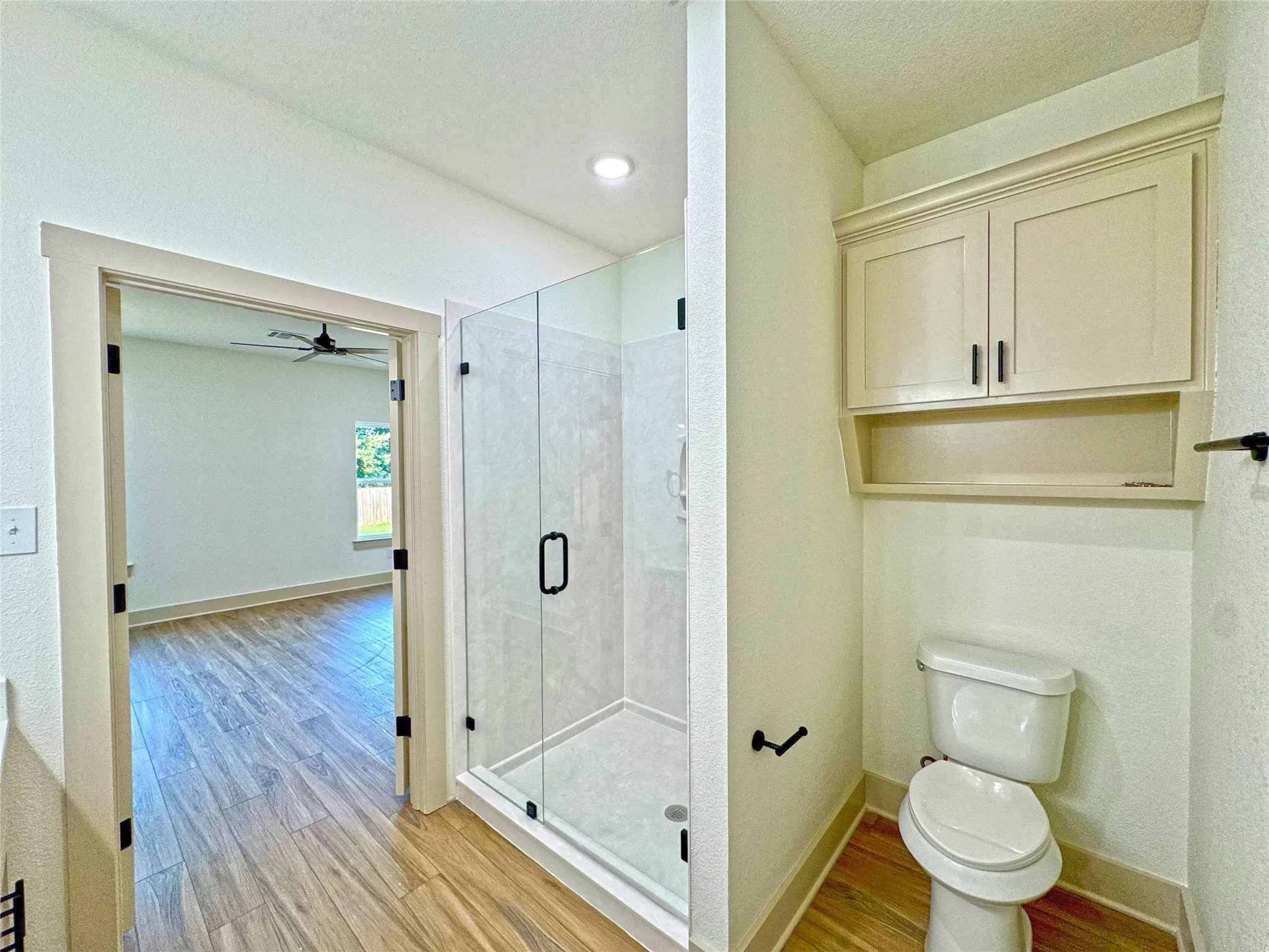 Full bath with a stall shower, light wood-style floors, and ceiling fan