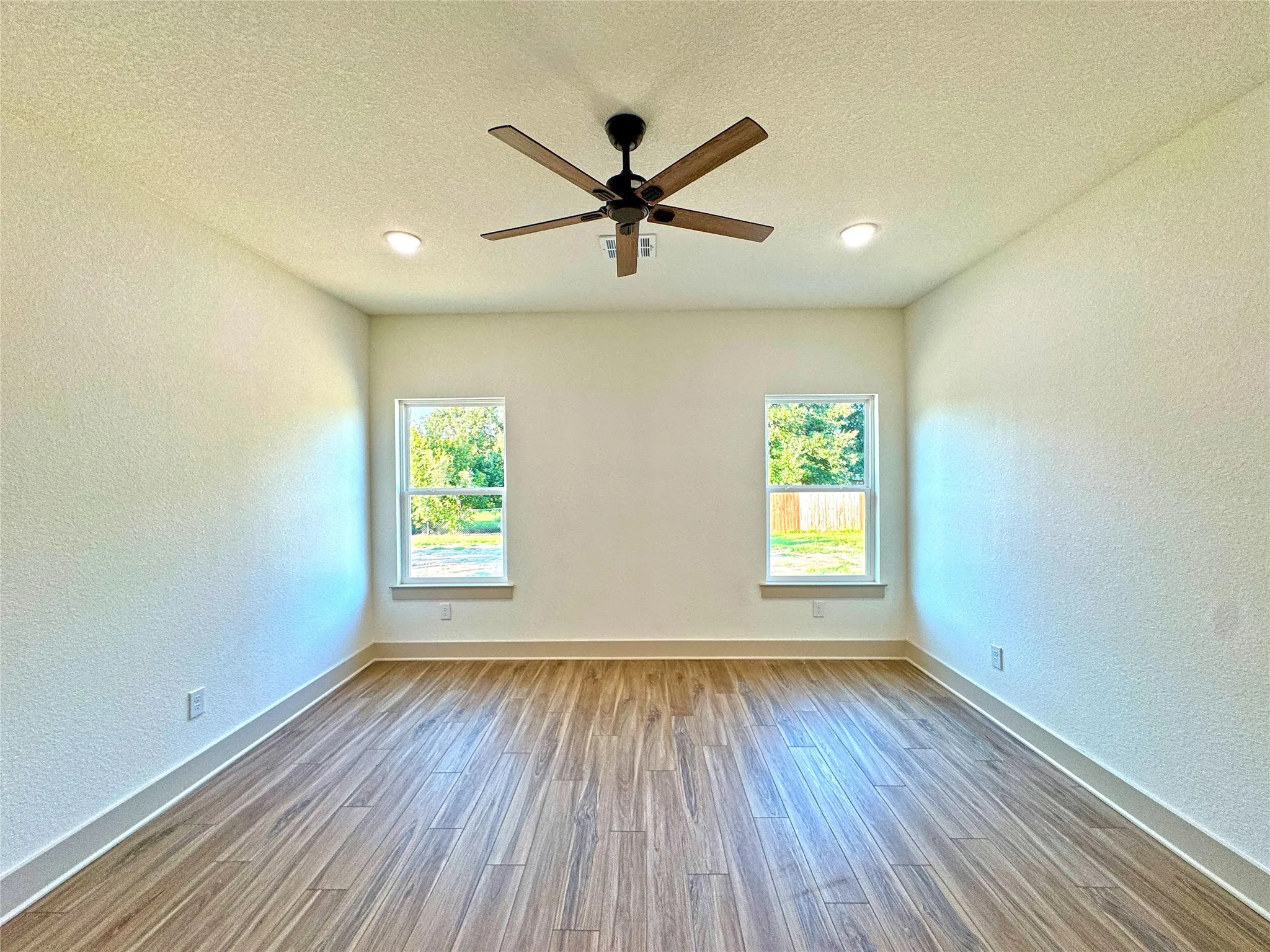 Spare room with a textured wall, a textured ceiling, ceiling fan, and wood finished floors