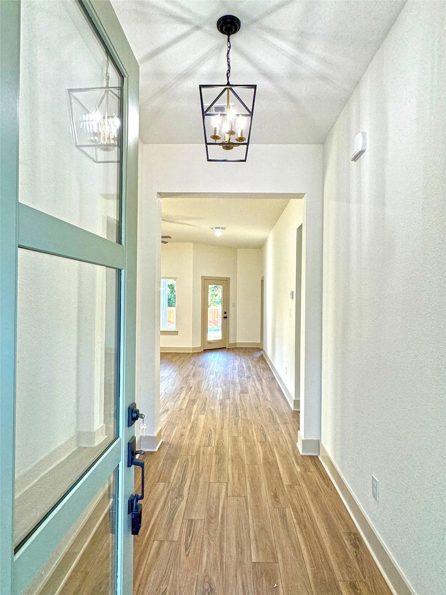 Hall featuring light wood finished floors and suspended lighting