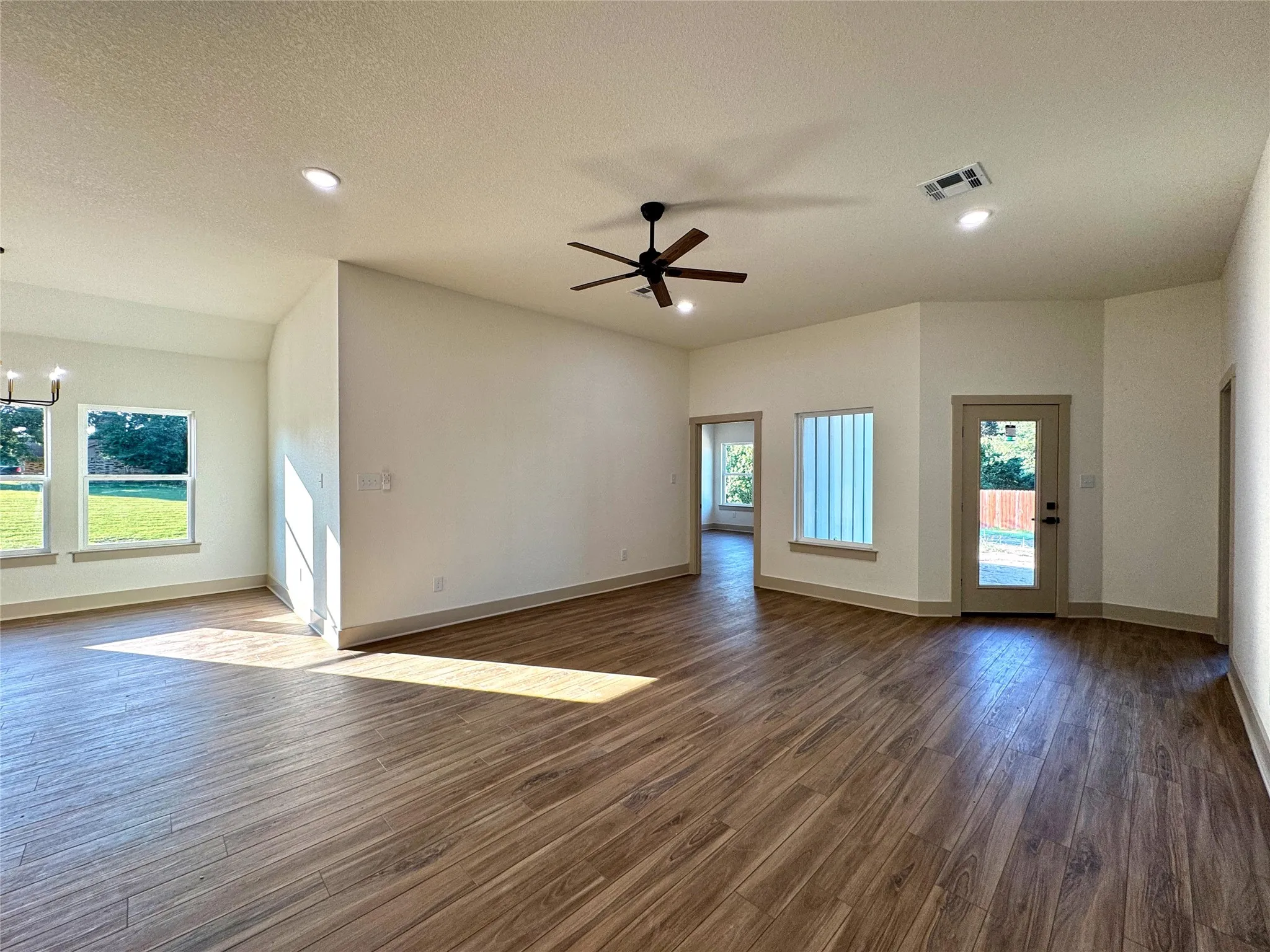 Empty room with dark wood finished floors, a ceiling fan, a textured ceiling, and suspended lighting