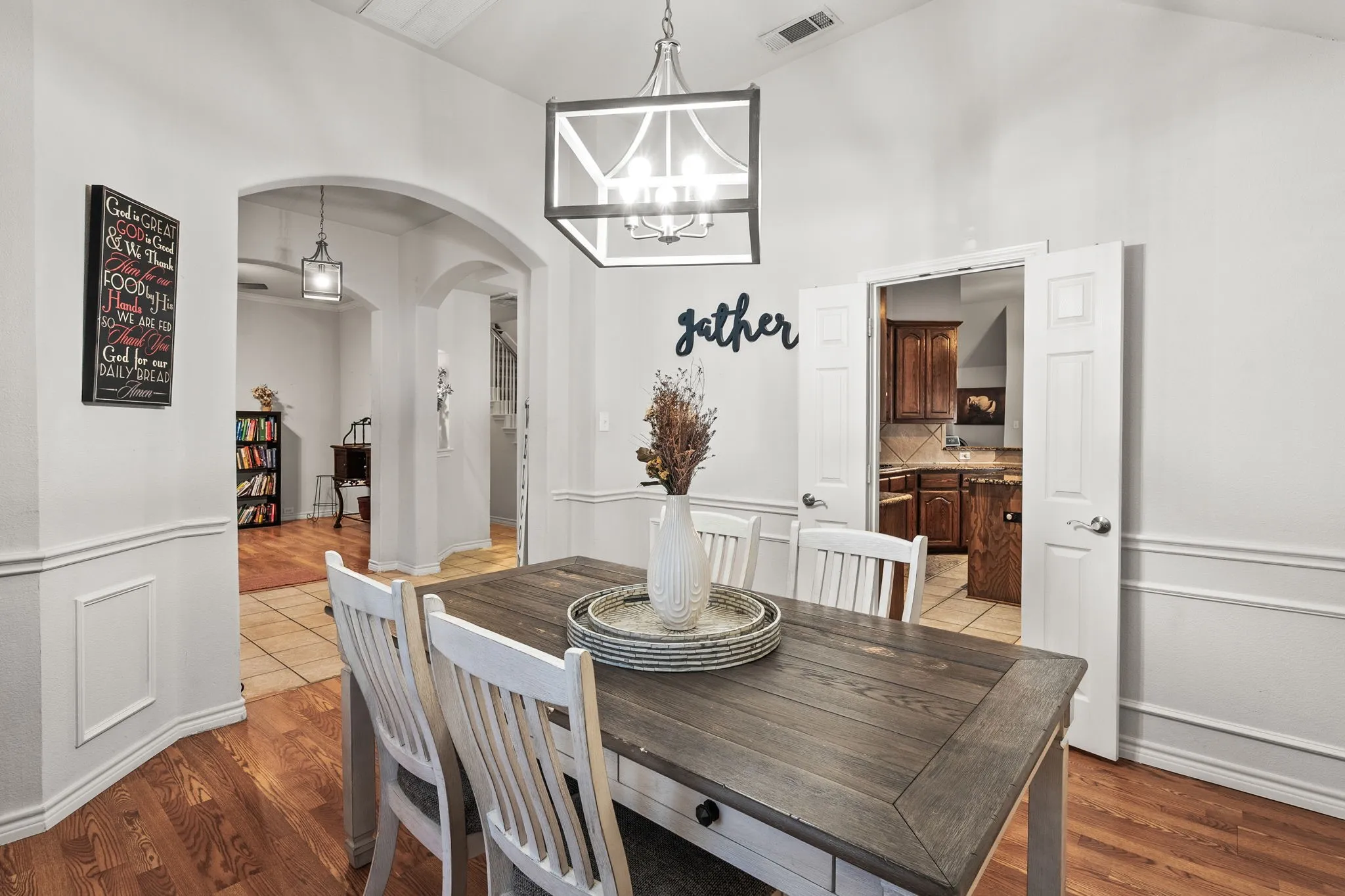 Dining room with wood finished floors, a chandelier, arched walkways, and a high ceiling