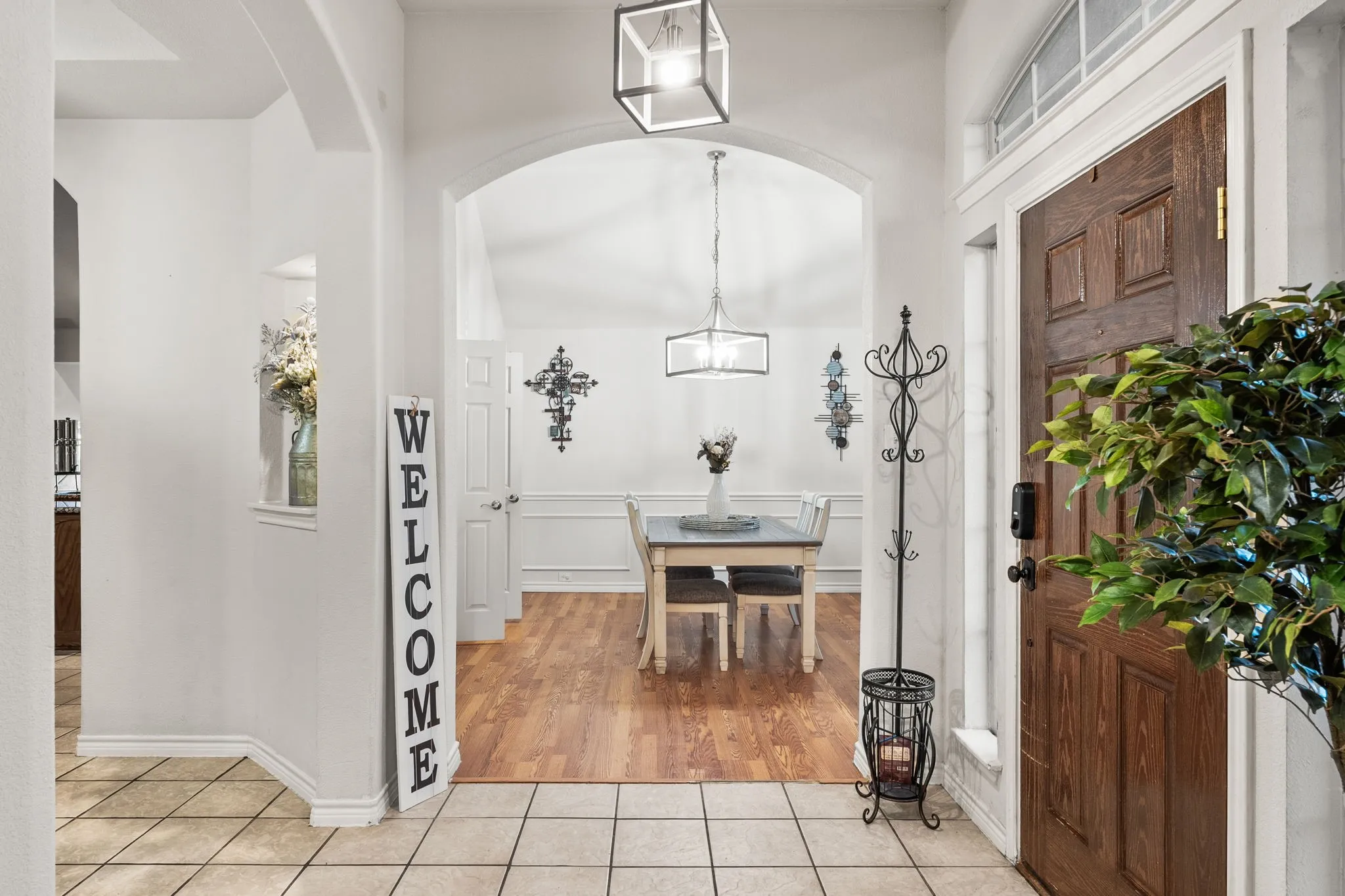 Tiled entryway with wainscoting, a decorative wall, and arched walkways