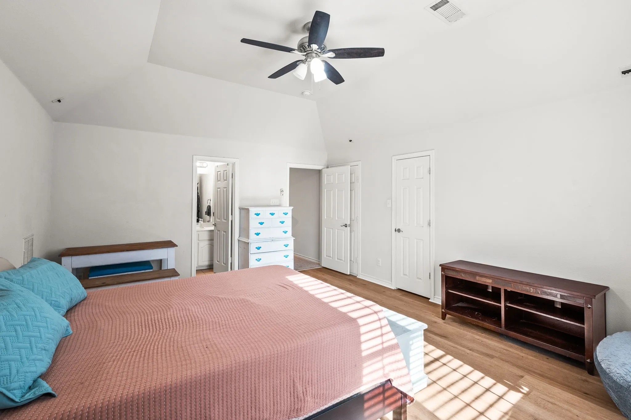 Bedroom with lofted ceiling, ceiling fan, wood finished floors, and ensuite bath