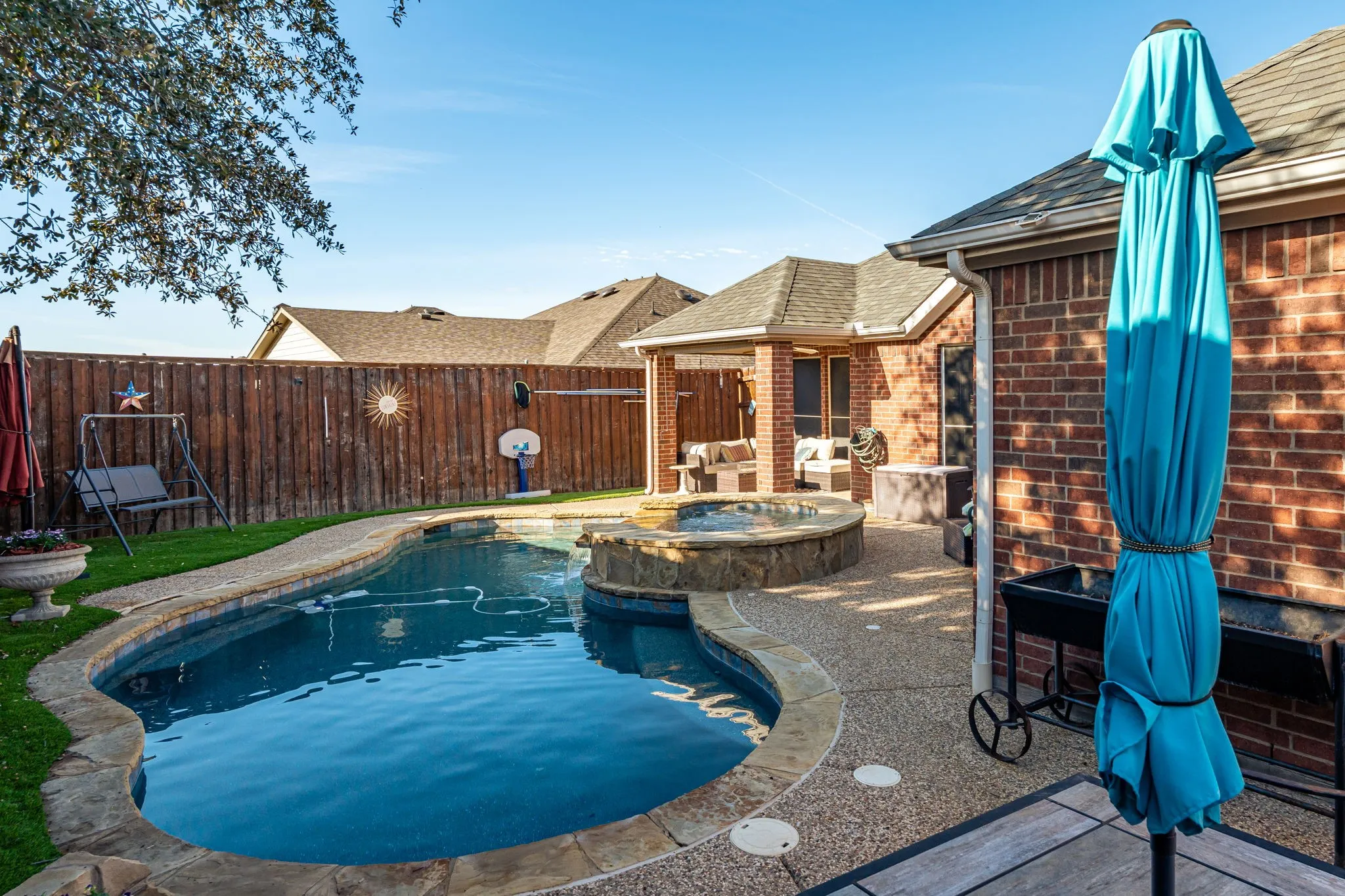 Combined pool / hot tub with a patio area and a fenced backyard