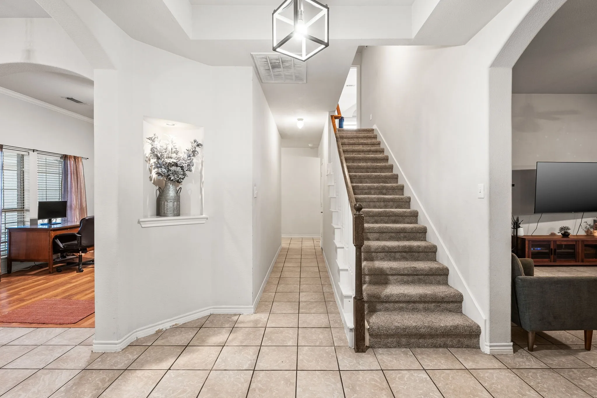 Stairway featuring arched walkways and tile patterned flooring