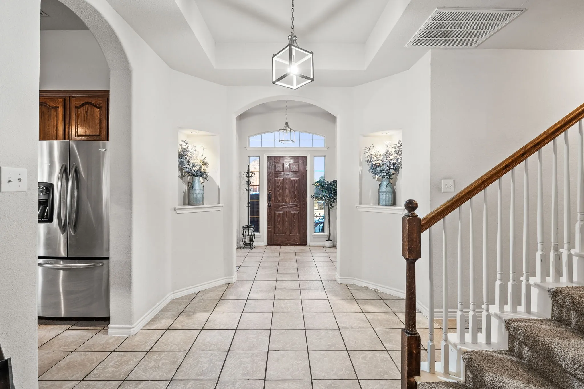 Foyer featuring arched walkways, light tile patterned floors, and a raised ceiling