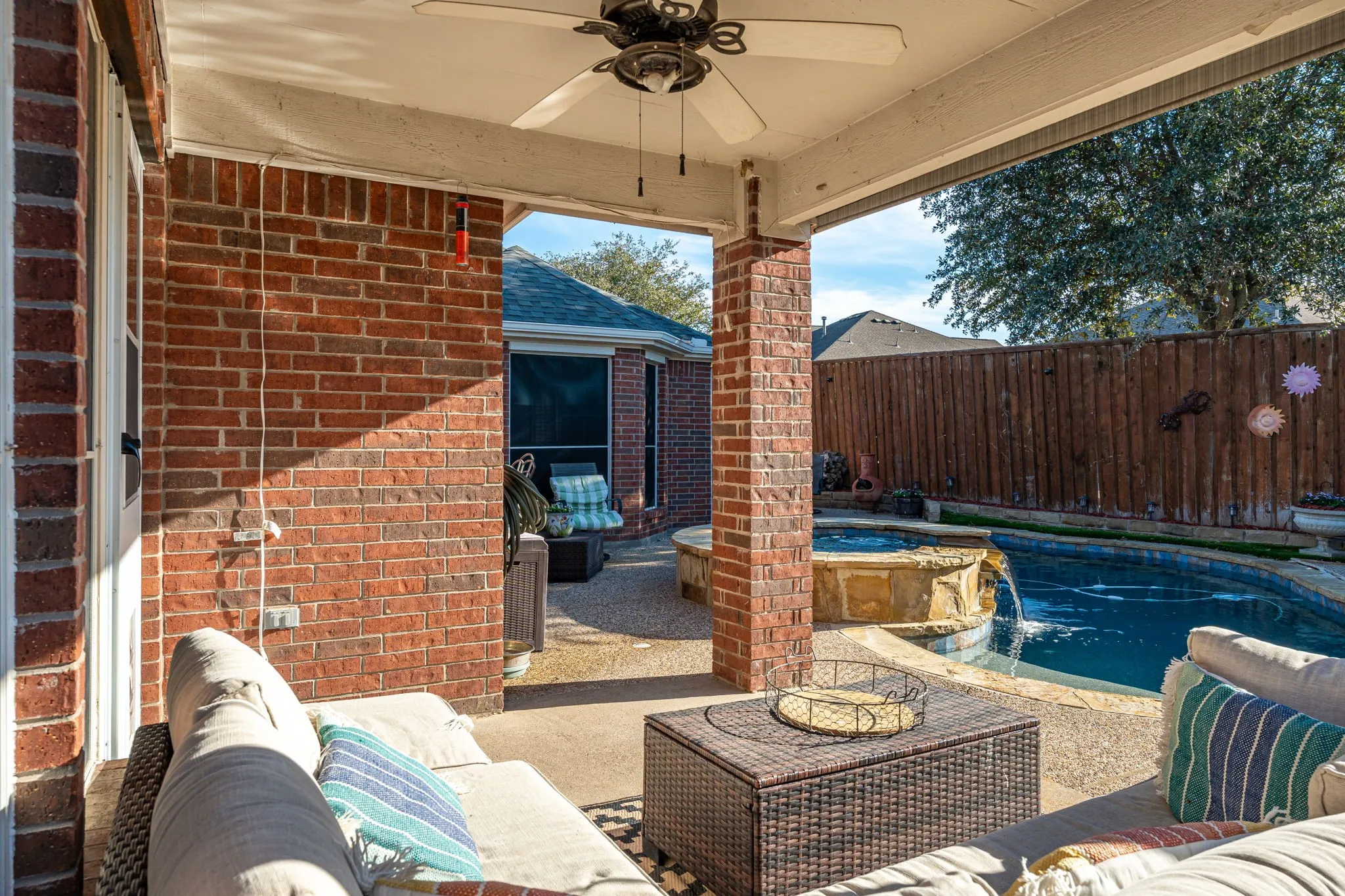 Fenced backyard with a ceiling fan, a patio area, outdoor seating, and a pool with connected hot tub