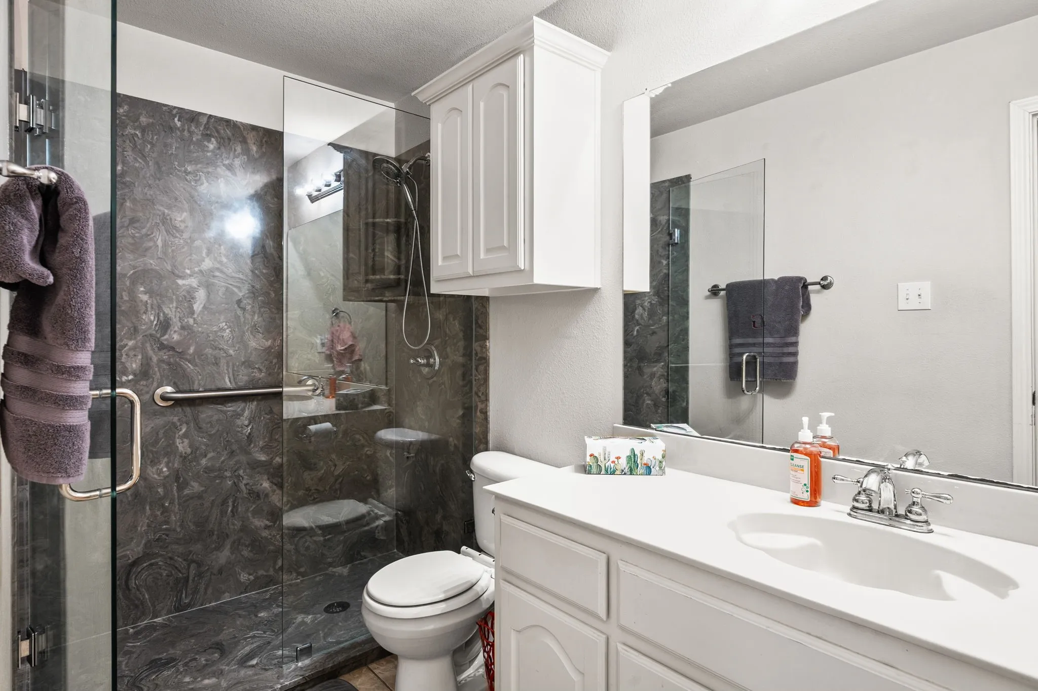 Full bathroom with a marble finish shower, vanity, and a textured ceiling