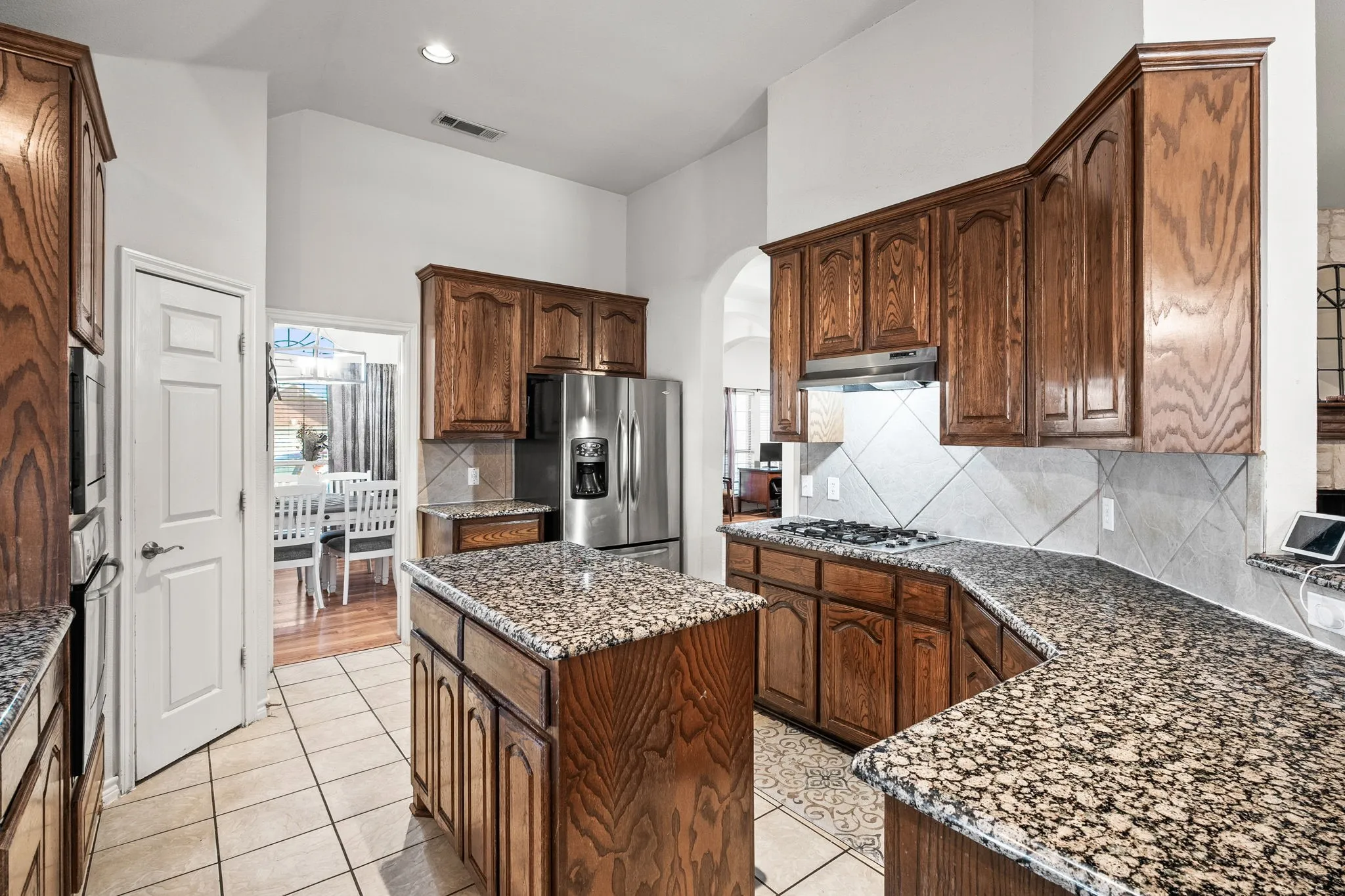 Kitchen with dark stone counters, decorative backsplash, arched walkways, a center island, and stainless steel appliances