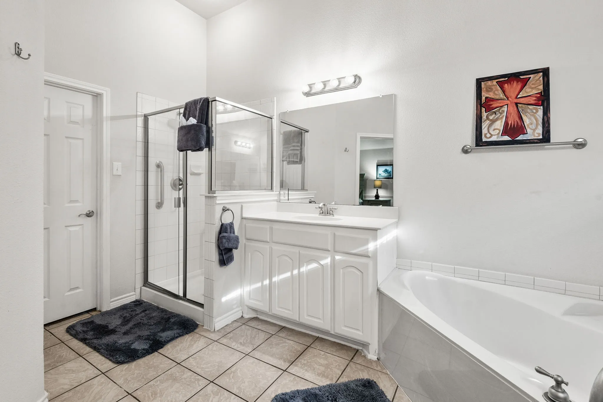 Bathroom featuring a garden tub, vanity, a stall shower, and light tile patterned floors
