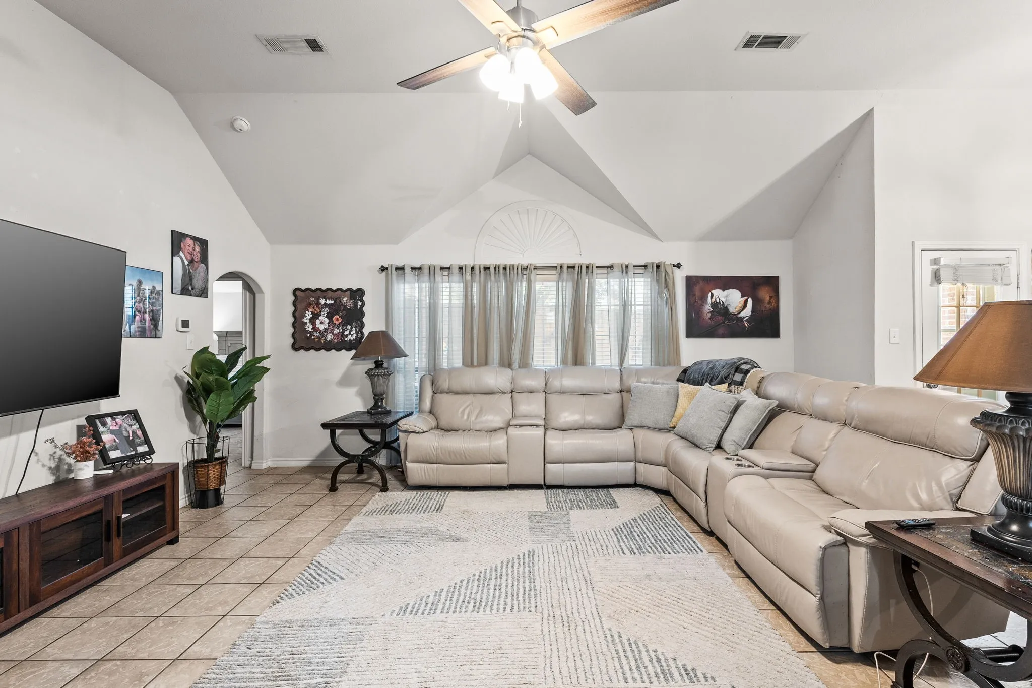 Living area featuring a ceiling fan, light tile patterned floors, and arched walkways