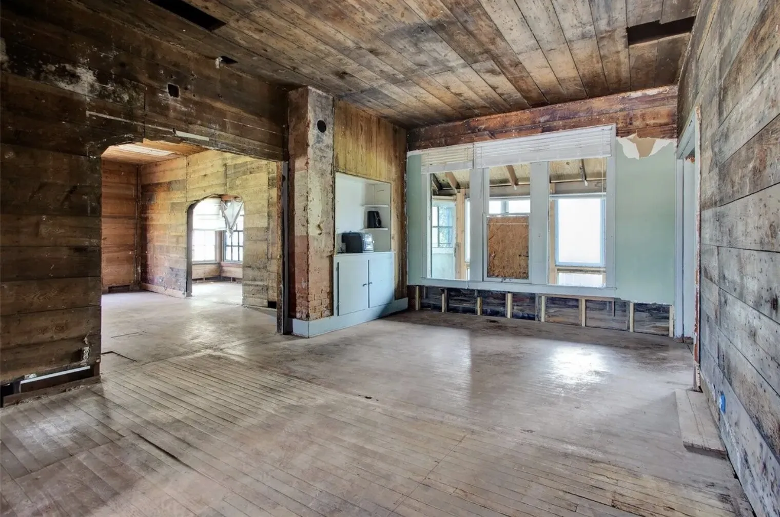 Empty room featuring arched walkways, hardwood / wood-style floors, wood walls, and wooden ceiling