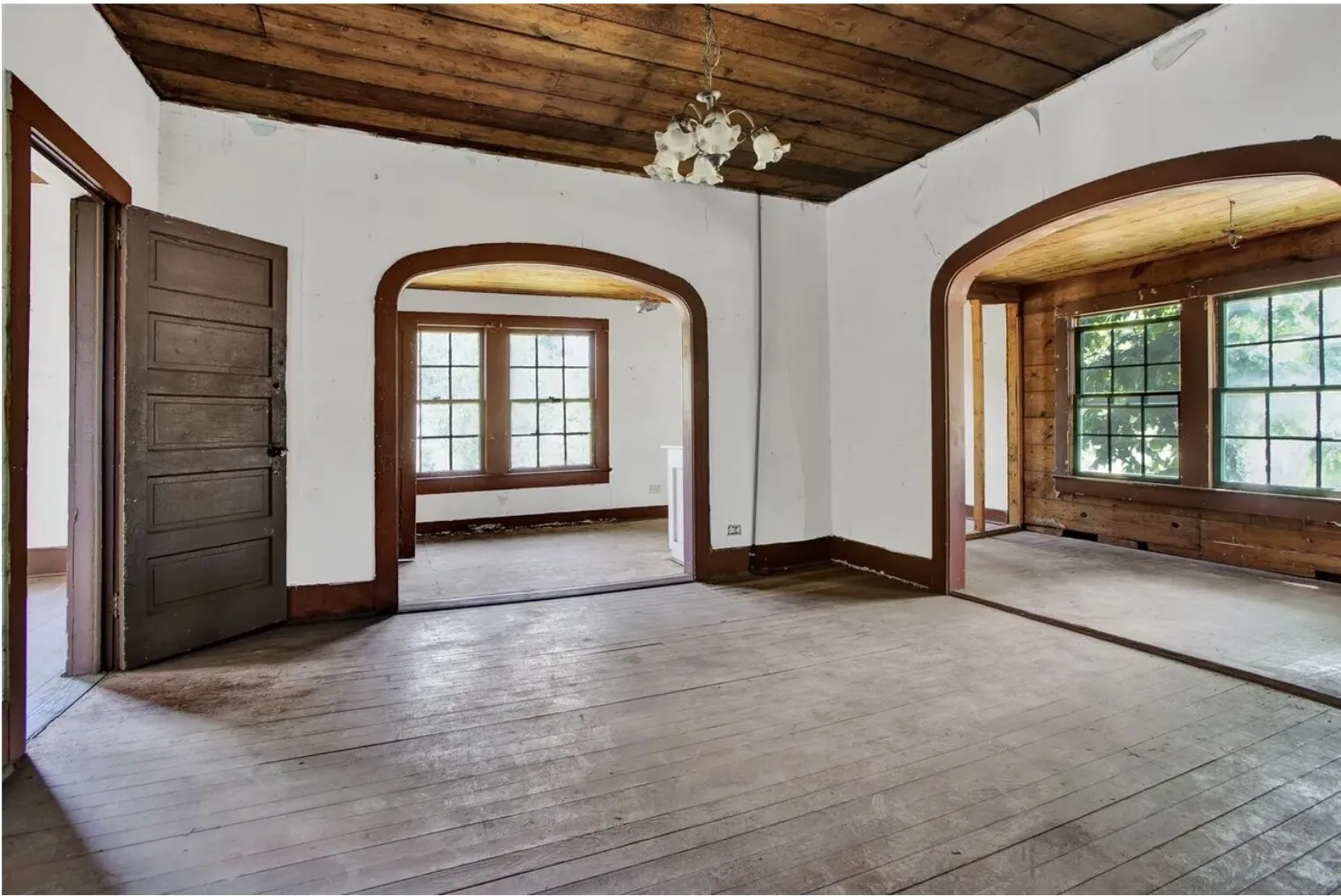 Spare room featuring wood ceiling, hanging lights, arched walkways, hardwood / wood-style flooring, and plenty of natural light