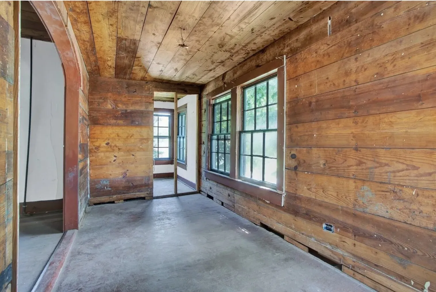 Empty room with wood walls, concrete floors, and wood ceiling