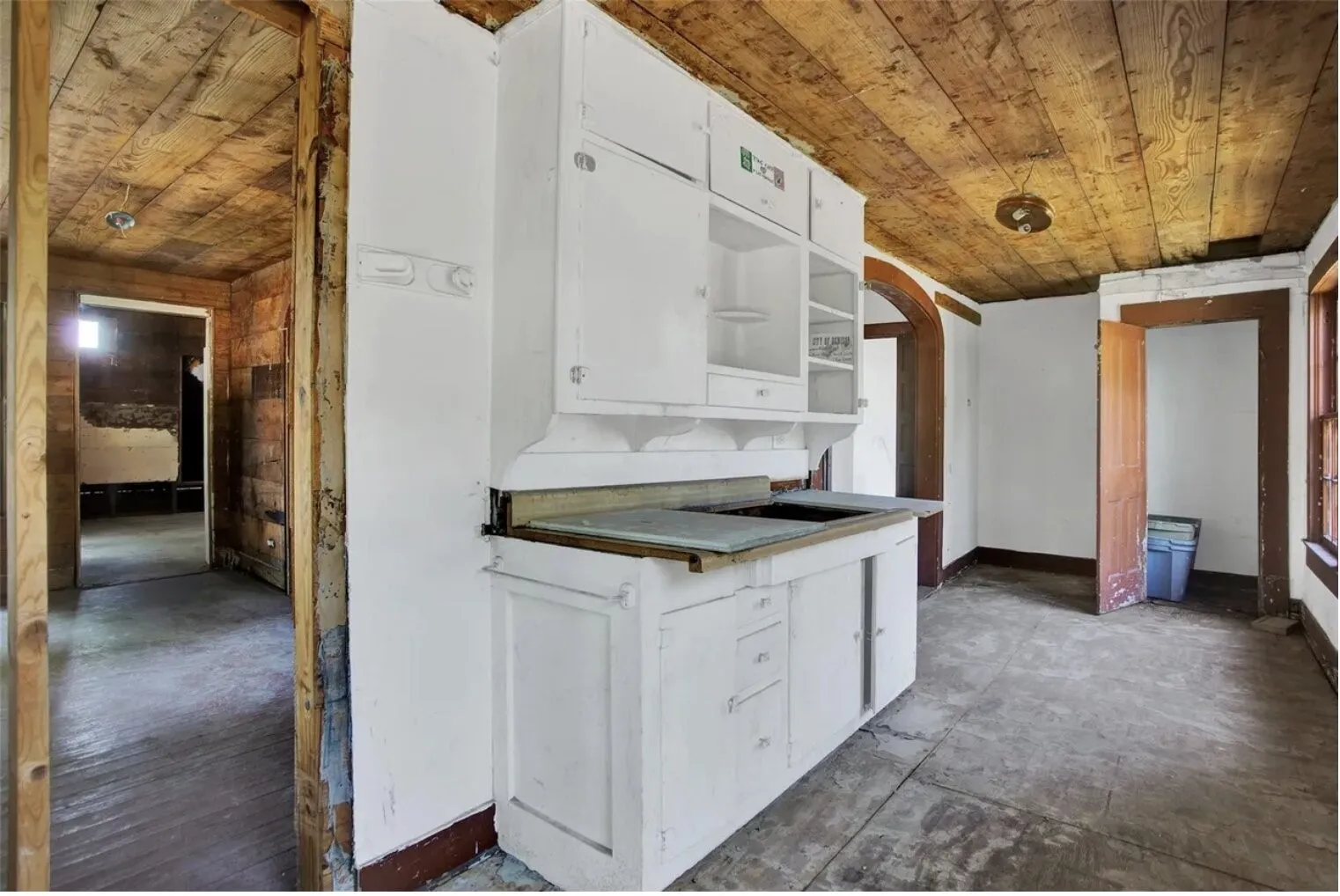 Kitchen featuring white cabinetry, open shelves, arched walkways, and wooden ceiling